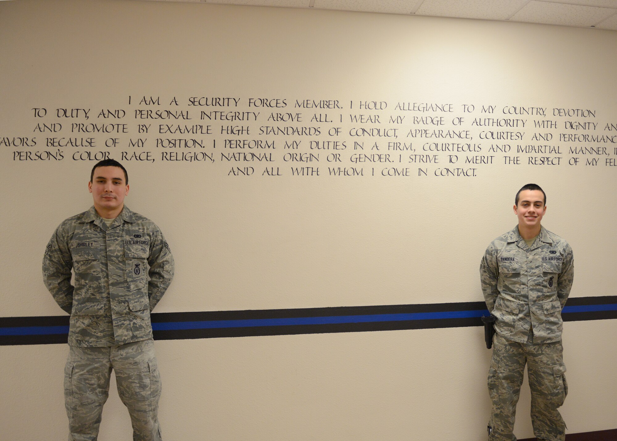 U.S. Air Force Senior Airman Patrick Shirley and Airman 1st Class Danny Banderas, 354th Security Forces Squadron response force leaders, stand in front of the security forces creed Feb. 26, 2015, Eielson Air Force Base, Alaska. Shirley and Banderas dedicated over 250 hours, painting 1,200 feet of the thin blue line and putting inspirational quotes throughout the security forces building. (U.S. Air Force photo by Senior Airman Ashley Nicole Taylor/Released)
