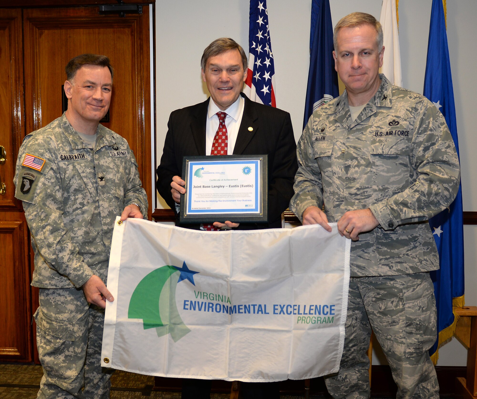 David Paylor, Virginia Department of Environmental Quality director, presents a certificate of appreciation and a flag to U.S. Army Col. William Galbraith, 733rd Mission Support Group commander, and U.S. Air Force Col. John J. Allen, 633rd Air Base Wing commander, during a ceremony honoring the 733rd Civil Engineer Division Environmental Element at Fort Eustis, Va., March 9, 2015. The 733rd CED was named an Extraordinary Environmental Enterprise, or E4, under the Virginia Environmental Excellence Program for its achievement and commitment to minimizing the installation’s environmental 