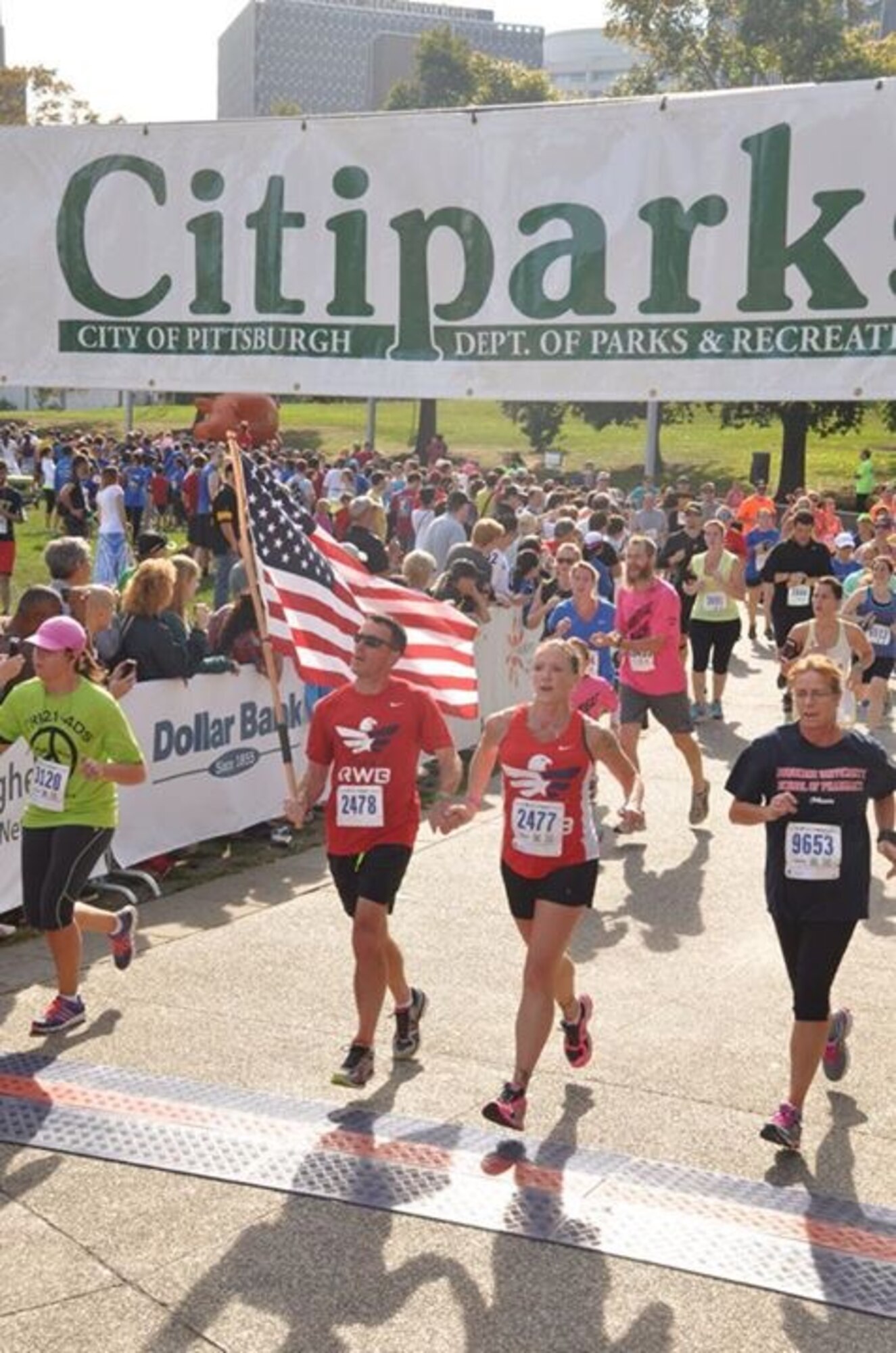 Tech. Sgt. John Davis, 911th Security Forces fire team leader, and his wife, Master Sgt. Jessica Davis, 911th Civil Engineering Squadron emergency management superintendent, cross the finish line together at the 2014 Pittsburgh Great Race. The two ran the race with other members of the Team RWB Western Pennsylvania Chapter, a nonprofit organization that they are both involved in. Team RWB’s mission is to enrich the lives of America’s veterans by connecting them to their community through physical and social activity. (U.S. Air Force courtesy photo)