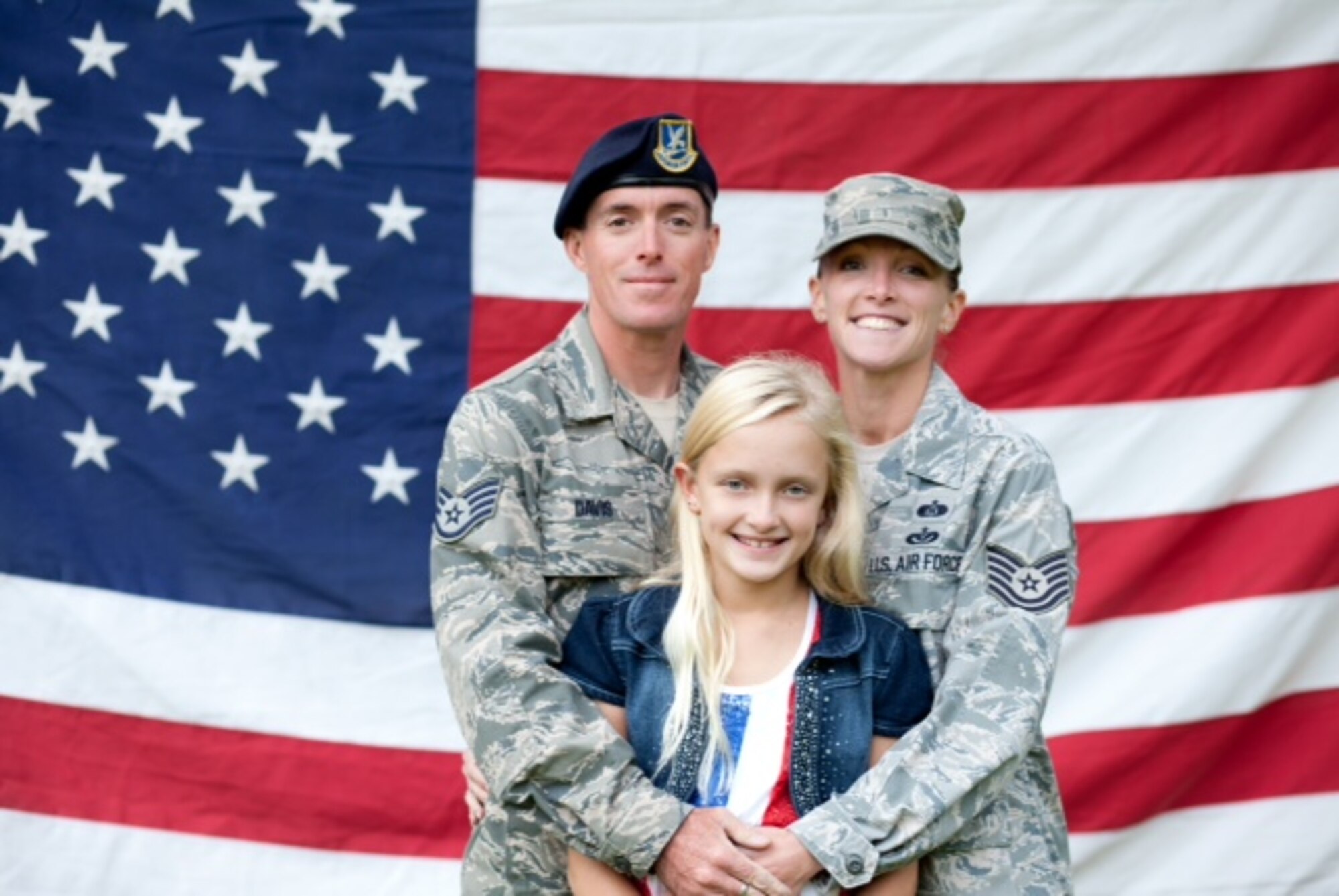 Tech. Sgt. John Davis, 911th Security Forces fire team leader, and his wife, Master Sgt. Jessica Davis, 911th Civil Engineering Squadron emergency management superintendent, pose in front of an American flag with their daughter. Together the couple has more than 24 years of military service. (U.S. Air Force courtesy photo)