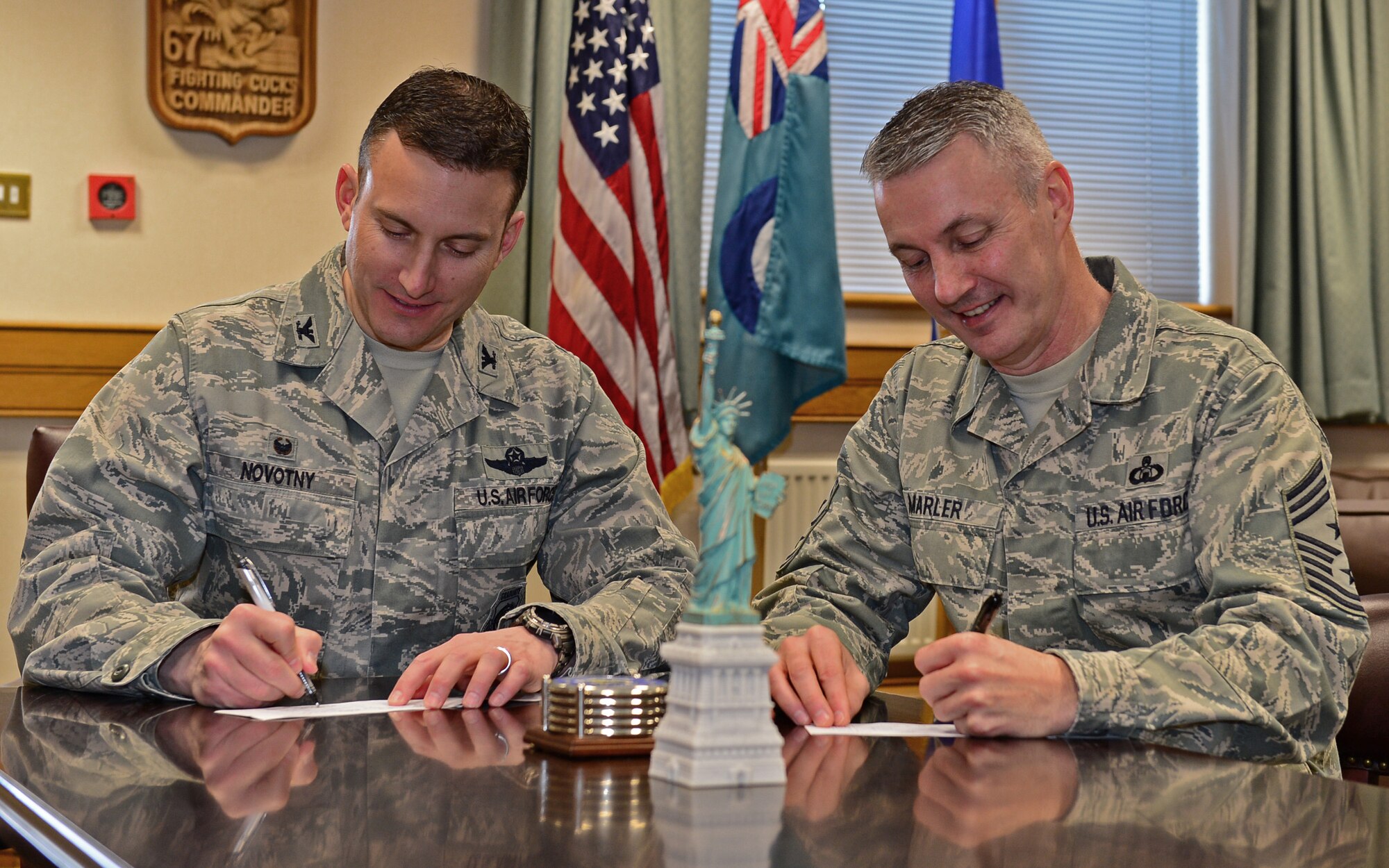 Col. Robert Novotny, 48th Fighter Wing commander, and Chief Master Sgt. Vincent Marler, 48th FW command chief, sign contributions to the 2015 Air Force Assistance Fund campaign at Royal Air Force Lakenheath, England, March 11, 2015. Contributions support the Air Force Aid Society, Air Force Enlisted Village, Air Force Village, and the Gen. and Mrs. Curtis E. LeMay Foundation. (U.S. Air Force photo by Airman 1st Class Erin R. Babis/Released)