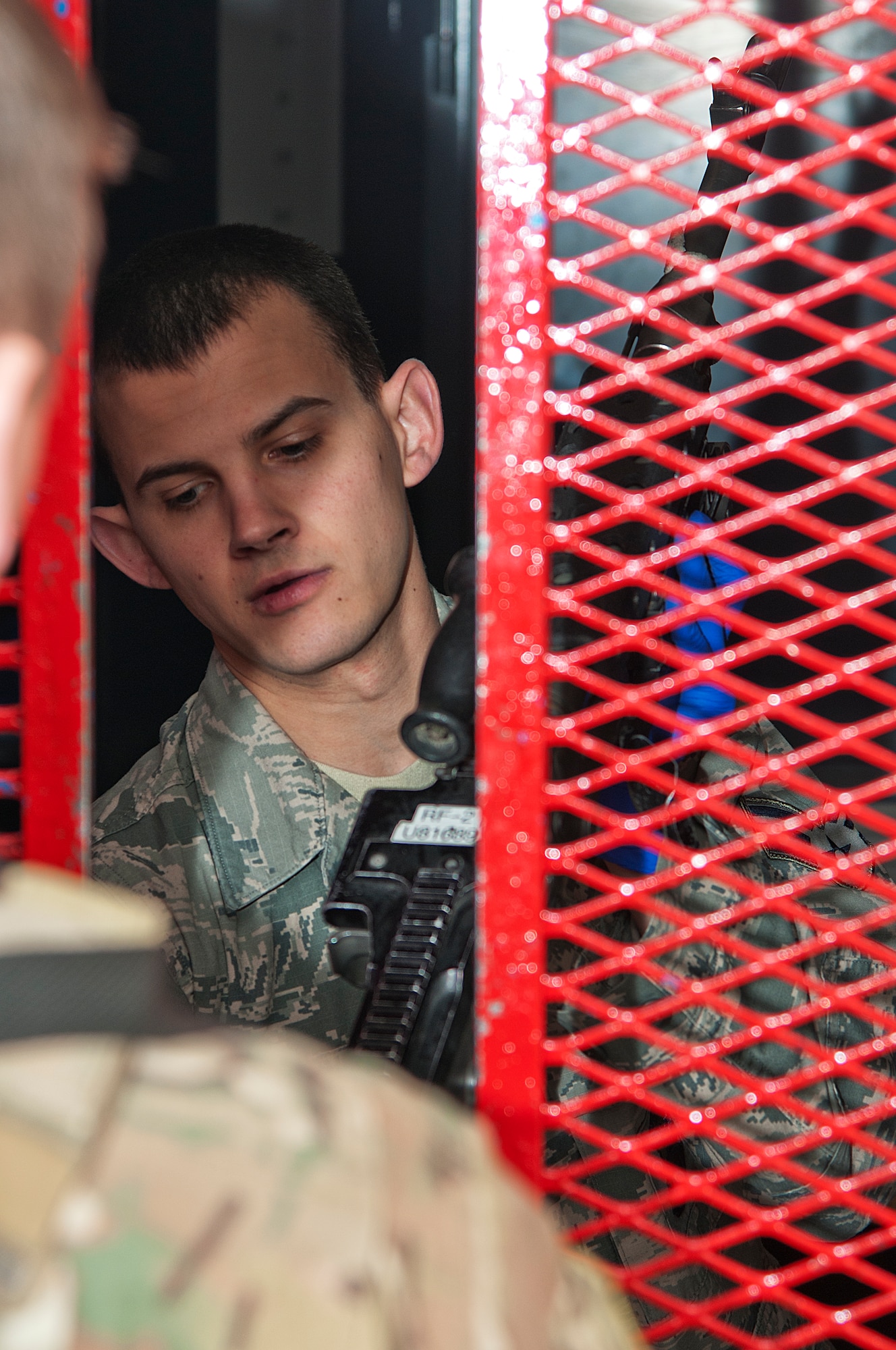 Senior Airman William Young, 90th Security Forces Group armorer, hands a security forces defender an M240 machine gun March 10, 2014, in the 90th SFG armory, F.E. Warren Air Force Base, Wyo. Each armorer checks for clearance against three lists before distributing gear to Airmen. (U.S. Air Force photo by Airman 1st Class Brandon Valle)  