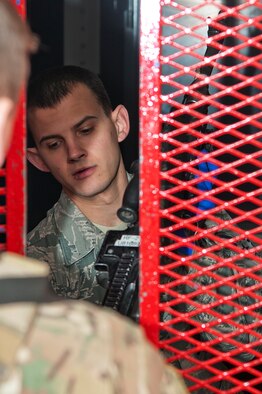 Senior Airman William Young, 90th Security Forces Group armorer, hands a security forces defender an M240 machine gun March 10, 2014, in the 90th SFG armory, F.E. Warren Air Force Base, Wyo. Each armorer checks for clearance against three lists before distributing gear to Airmen. (U.S. Air Force photo by Airman 1st Class Brandon Valle)  