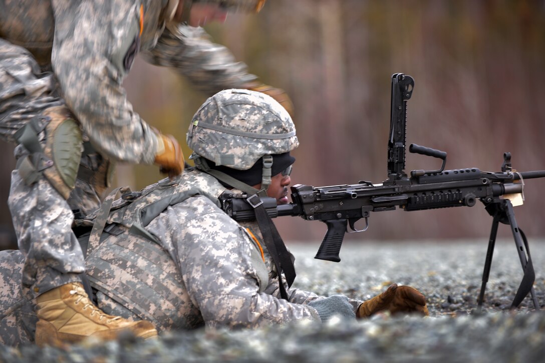 Army Pfc. James Travis receives instruction on the M249 Squad Automatic ...