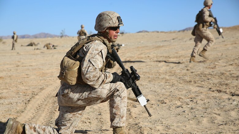 Cpl. Kevin A. Miller, team leader with 2nd Platoon, Company A, Ground Combat Element Integrated Task Force, observes his fire team as they advance on their objective during a Marine Corps Operational Test and Evaluation Activity assessment at Range 107, Marine Corps Air Ground Combat Center Twentynine Palms, March 7, 2015. From October 2014 to July 2015, the GCEITF will conduct individual and collective level skills training in designated ground combat arms occupational specialties in order to facilitate the standards-based assessment of the physical performance of Marines in a simulated operating environment performing specific ground combat arms tasks. 