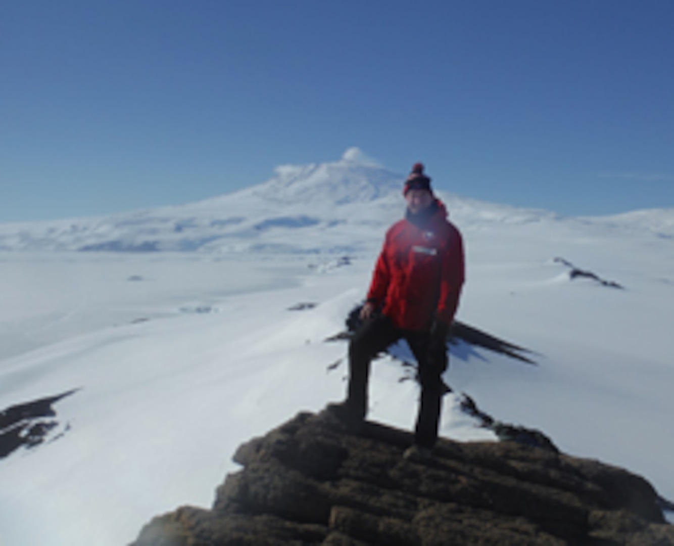 U.S. Air Force Chaplain Maj. Pete Drury stands atop Castle Rock, about an eight-mile hike from the town of McMurdo, with Mt. Erebus in the background. Chaplain Drury completed a deployment to Antarctica in support of Operation Deep Freeze, which in turn supports the United States Antarctic Program scientific research efforts.