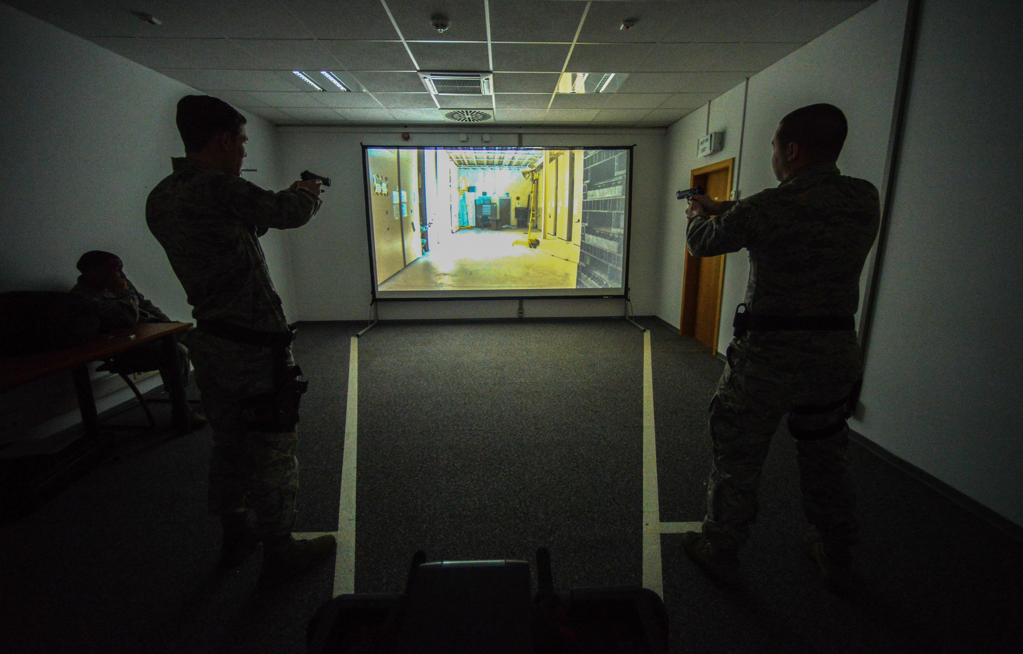 Airmen assigned to the 86th Security Forces Squadron react to a scenario during a Firearms Training System scenario March 6, 2015, at Ramstein Air Base, Germany. The training course helps give Airmen the confidence to react during real-world situations. (U.S. Air Force photo/Senior Airman Nicole Sikorski)