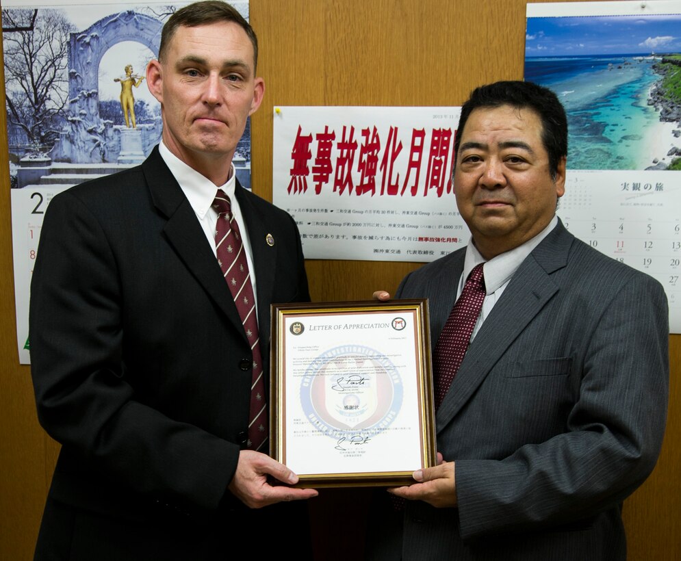 U.S. Marine Chief Warrant Officer Joseph Ponte, left, poses alongside Kazunari Agarie with the letter of appreciation awarded to Okito Taxi Company Feb. 24 during a visit to Okito Taxi Company in Urasoe City, Okinawa. The Okito Taxi Company, contracted with the Army and Air Force Exchange Service, was recognized not only for their efforts in solving a credit card fraud case, but also turning in items left in taxis by service members. “In law enforcement, we rely on many different relationships with people who may have information to help us solve our investigations,” said Ponte, a native of Portsmouth, Va. “(Okinawa law enforcement and businesses) play an important part in solving our cases. Their cooperation helps us maintain evidence to hold offenders accountable for crimes they have committed.”  Ponte is the investigations officer with the Criminal Investigation Division, Provost Marshal’s Office, Marine Corps Installations Pacific-Marine Corps Base Camp Butler, Japan. Agarie is the chief executive officer of Okito Taxi Company. 