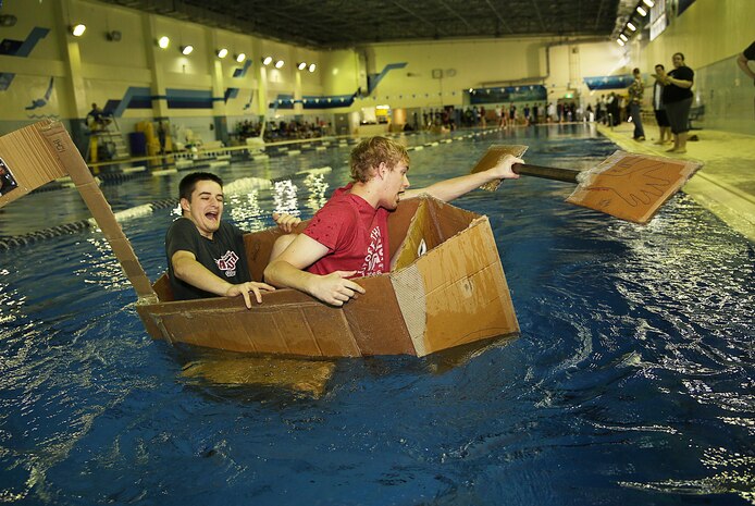 Students of Matthew C. Perry High School struggle to stay in their handmade, cardboard boats during a cardboard boat science competition held at the IronWorks pool aboard Marine Corps Air Station Iwakuni, Japan, March 12, 2015. In three days, students attempted to create a vessel that could sustain a 50-meter venture in the Olympic sized pool with two passengers, one of whom would use a handmade-cardboard paddle to row.
