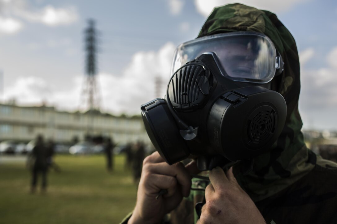 U.S. Marine Corps Cpl. Jeffrey Schott, motor transportation mechanic, with 3rd Transportation Support Battalion (TSB), Combat Logistics Regiment 3, 3d Marine Logistics Group, puts on a gas mask during a field meet at Godfrey Field, Camp Foster, Okinawa, Japan, Nov. 21, 2014. The field meet was organized with events that simulated combat situations and a tug of war for the companies of 3rd TSB to compete with one another. (U.S. Marine Corps photo by MCIPAC Combat Camera Lance Cpl. Robert Gonzales/Released)