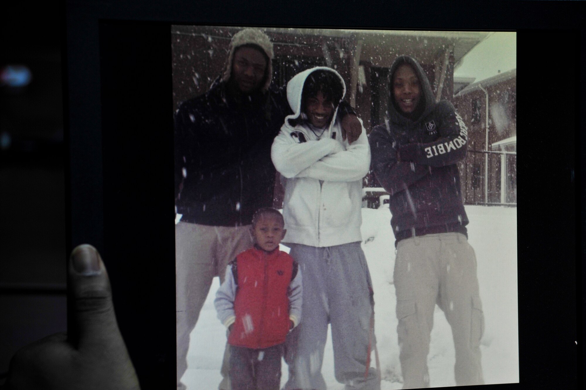 U.S. Air Force Airman 1st Class Elijah Rasheed looks at a photo of himself, his youngest brother Riley, cousin Daqwan, and brother Xavier (left to right) at Misawa Air Base, Japan, Feb. 10, 2015. Rasheed took on the responsibility of a father-figure for his brothers when drugs took hold of his parents’ lives. (U.S. Air Force photo by Senior Airman Jose L. Hernandez-Domitilo/Released)