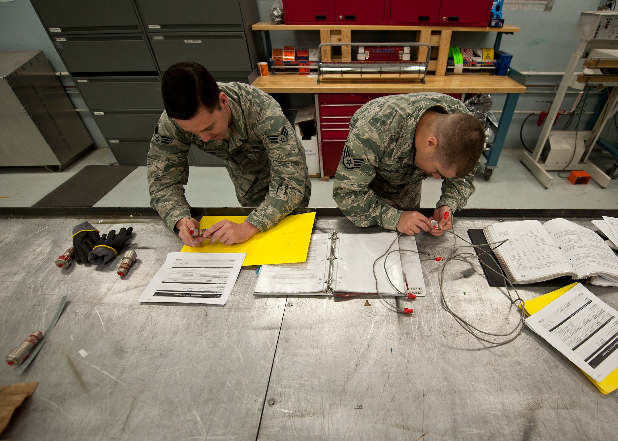 Senior Airman Peter Clark, left, and Staff Sgt. Martin Giuntoli, both 57th Maintenance Squadron munitions inspectors, perform an inspection on ejection seat parts at the munition inspection shop on Nellis Air Force Base, Nev., March 10, 2015. Inspections are completed regularly to make sure the items are serviceable, which helps ensure pilot’s safety. (U.S. Air Force photo by Staff Sgt. Siuta Ika)