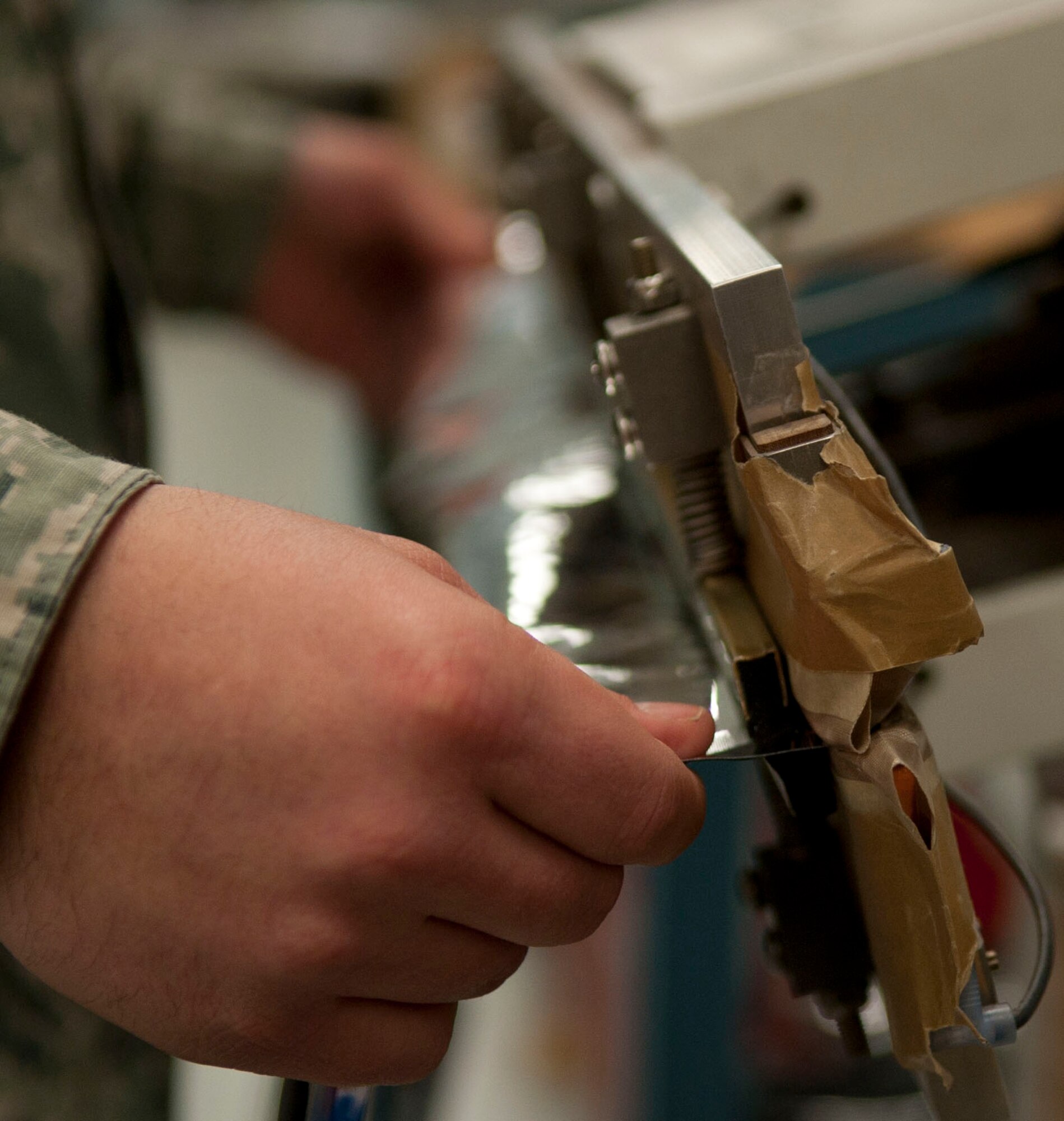 Senior Airman Peter Clark, 57th Maintenance Squadron munitions inspector, cuts material to make a heat sealing bag at the munitions inspection shop on Nellis Air Force Base, Nev., March 10,2015.  The barrier bag helps prevent static electricity.  (U.S. Air Force photo by Airman 1st Class Mikaley Towle)