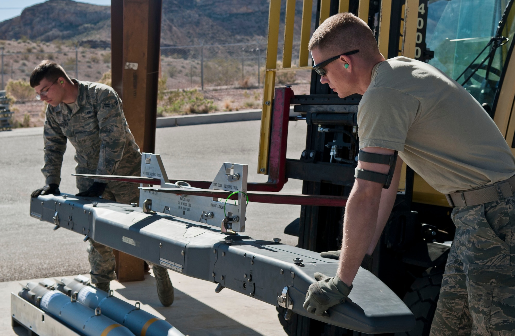 Airman 1st Class Austin Woosley, left, 57th Maintenance Squadron, and Senior Airman Forrest Patten, Offutt Air Force Base, Neb., 55th Maintenance Squadron stockpile surveillance member, prepares a munition before it can be attached to an aircraft at the munitions storage area on Nellis Air Force Base, Nev., March 5, 2015. AMMO has 11 different shops that work together to ensure that the day-to-day mission gets done. (U.S. Air Force photo by Airman 1st Class Mikaley Towle)