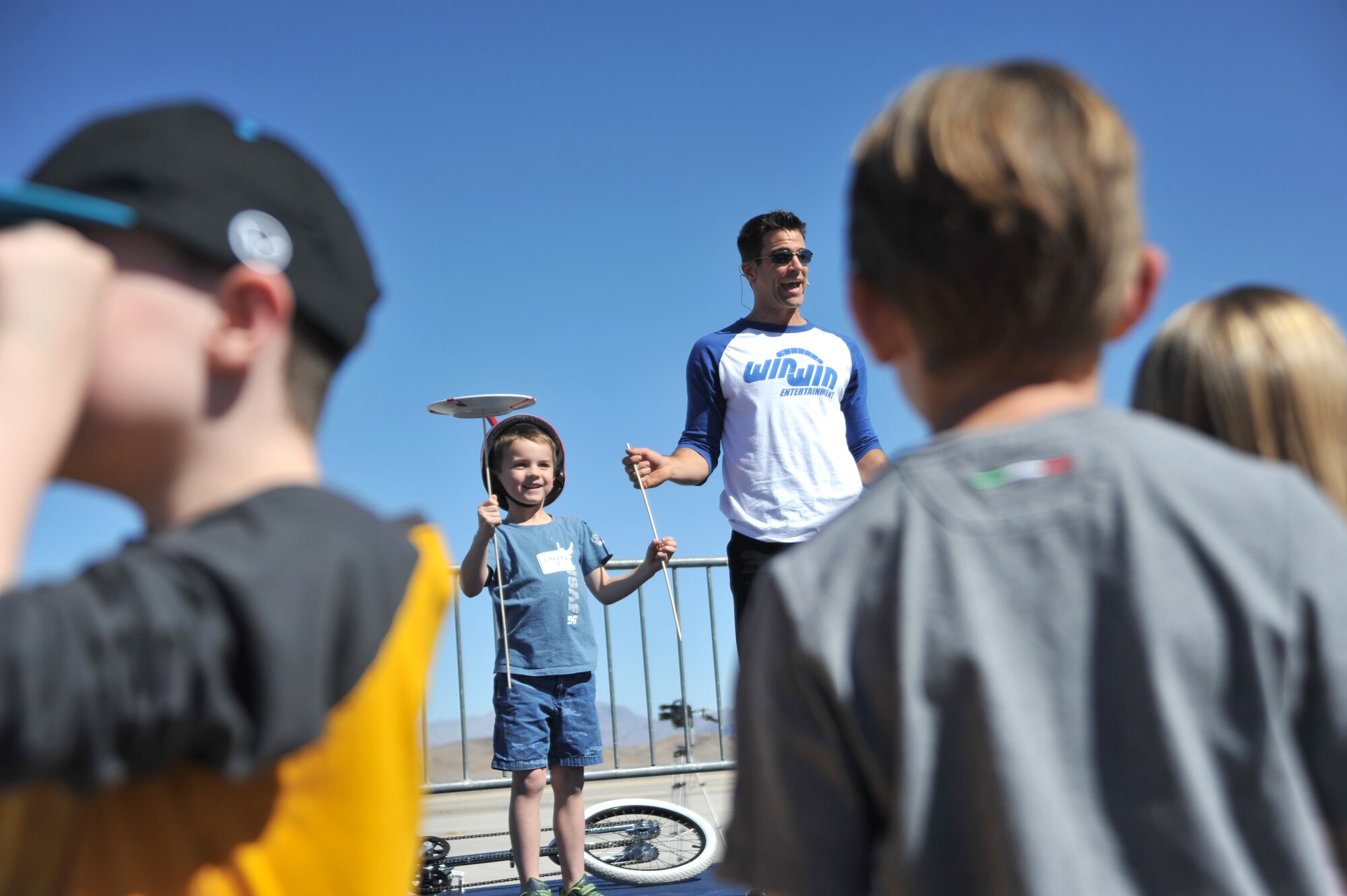 An Indian Springs Appreciation Day spectator, balances spinning plates with the help of Jeff Civillico, Las Vegas entertainer, during a performance for Indian Springs Appreciation Day March 10, 2015, at Creech Air Force Base, Nevada. Civillico performed an interactive comedy act for the Indian Springs community and base members and their families. (U.S. Air Force photo by Airman 1st Class Christian Clausen/Released)