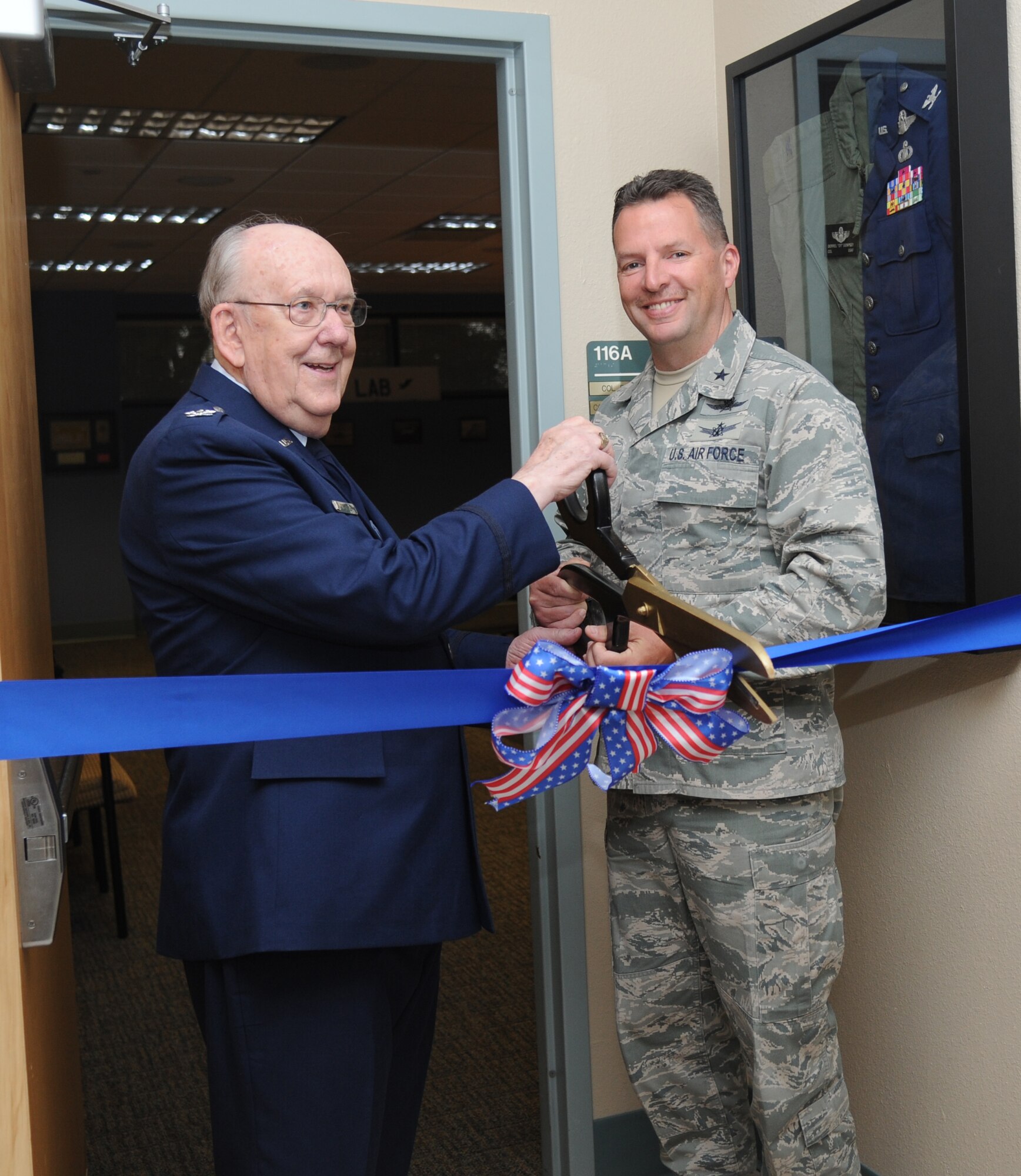 Retired Air Force Col. Derrel Dempsey and Brig. Gen. Patrick Higby, 81st Training Wing commander, prepare to cut the ribbon during a room dedication ceremony in Dempsey’s honor March 9, 2015, at Cody Hall, Keesler Air Force Base, Miss.  The 334th Training Squadron dedicated the building’s conference room in honor of Dempsey’s military accomplishments. The Air Force's award for the most outstanding air traffic control officer manager of the year is named in his honor. Dempsey has 30 years of Air Force aviation experience. In his final assignment as deputy chief of staff for Air Force Communication Command's air traffic services, he deployed more than 642 combat-ready Air Force air traffic controllers to 75 Federal Aviation Administration facilities during the 1981 air traffic controller strike. (U.S. Air Force photo by Kemberly Groue)