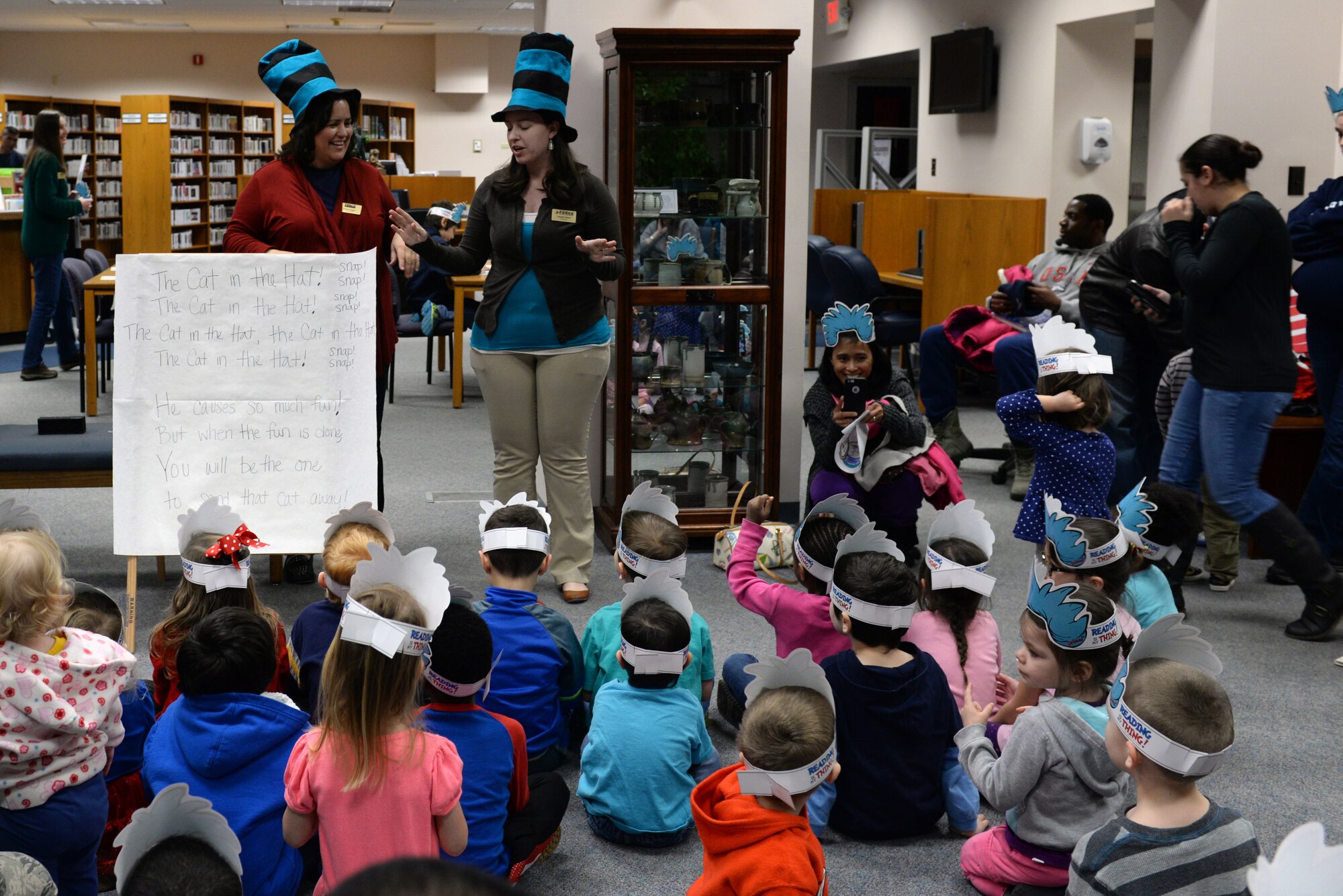 Donna Panger and Amanda James lead children in a song about "The Cat in the Hat," a Dr. Seuss character, during a birthday party held in his honor at the library at Scott Air Force Base, Illinois on March 5, 2015. The birthday party started with a sing-along and story time. Panger is a library technician and James is a library aide at the 375th Force Support Squadron library. (U.S. Air Force photo by Senior Airman Sarah Hall-Kirchner/Released)