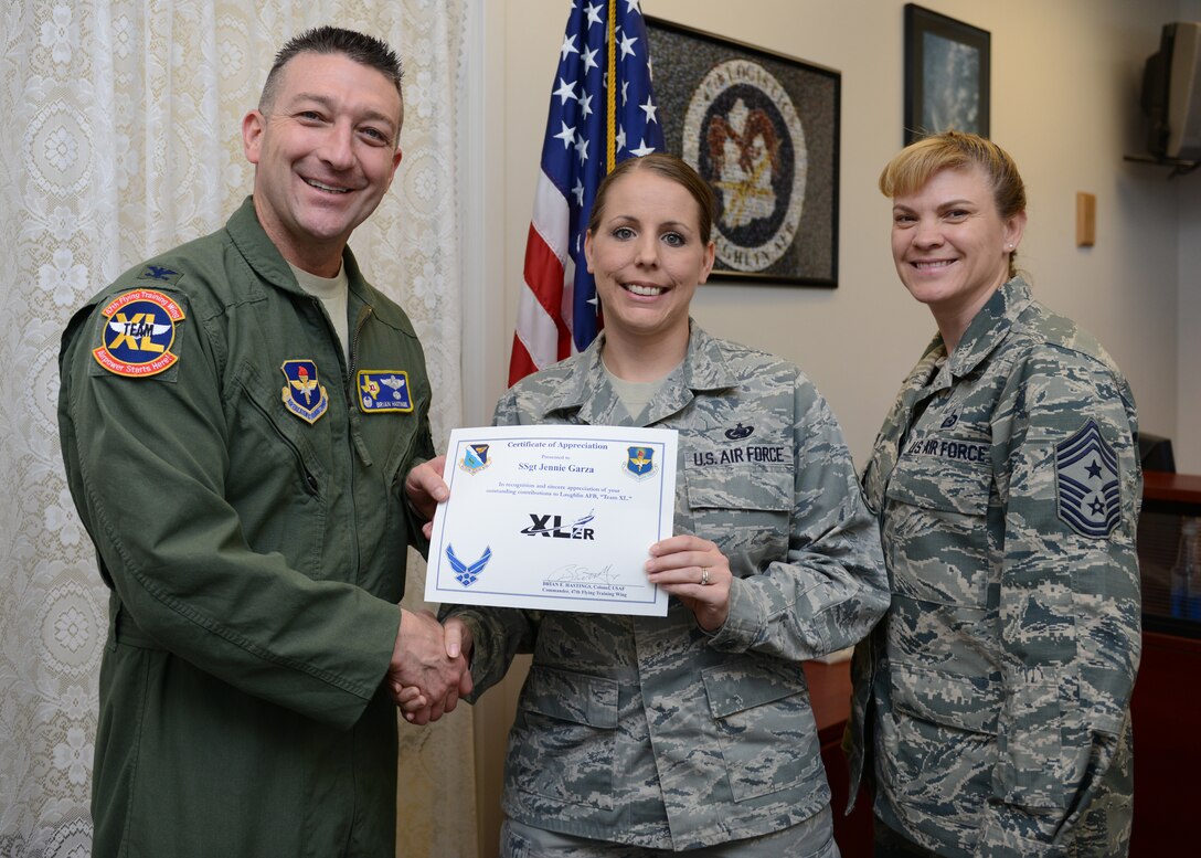 Staff Sgt. Jennie Garza, center, 47th Logistics Readiness Flight NCO in charge of logistics plans, poses with Col. Brian Hastings, left, 47th Flying Training Wing commander and Chief Master Sgt. Teresa Clapper, right, 47th FTW command chief, after accepting the XLer of the week award here March 11, 2015. The XLer is a weekly award chosen by wing leadership and was presented to Garza for her work in rewriting the installation deployment plan which helped streamline the 166 page document. (U.S. Air Force photo by Airman 1st Class Jimmie D. Pike)(Released)