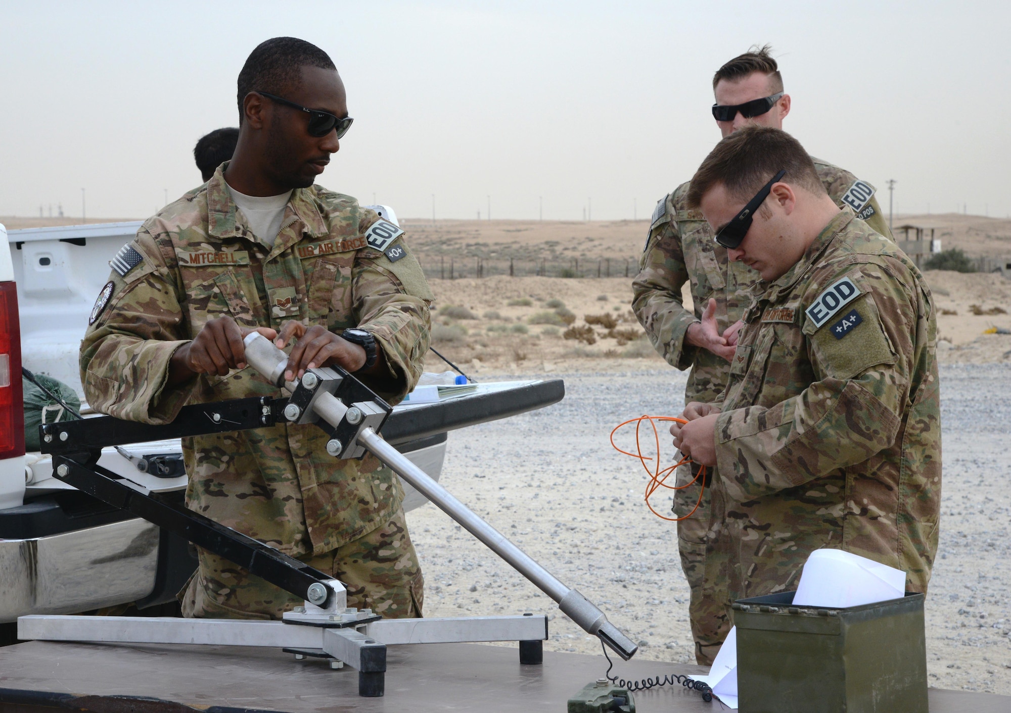 Staff Sgt. John Mitchell (left) and Senior Airmen Jeff Glover (right), 386th Expeditionary Civil Engineer Squadron Explosive Ordnance Disposal technicians, explain the capability of a recoil absorbing mechanism, which is used to disrupt the circuity of a bomb, here March 6, 2015.  EOD Airmen are responsible for locating and neutralizing potential explosive devices, as well as clearing the airfield of hazardous munitions. (U.S. Air Force photo by 1st Lt. Sarah Ruckriegle)