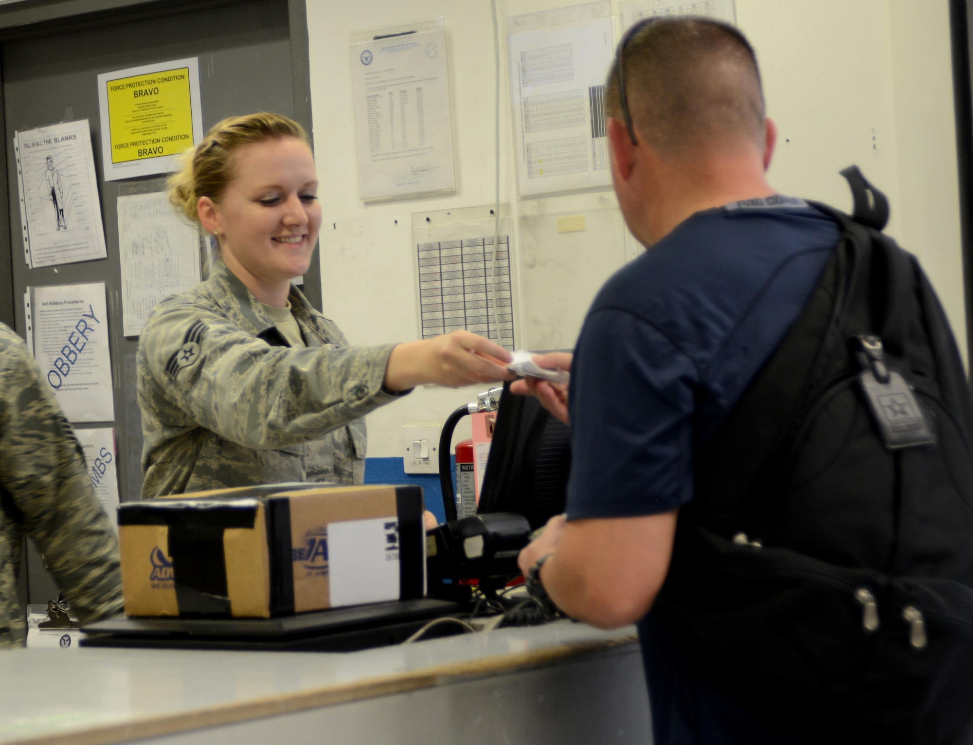 U.S. Air Force Senior Airman Stacie Rhodes, left, 379th Expeditionary Communications Squadron, hands a receipt to a customer, March 10, 2015, at Al Udeid Air Base, Qatar. The post office is just one of many morale-based mission sets that the 379th ECS provides to servicemembers here. (U.S. Air Force photo by Senior Airman Kia Atkins)