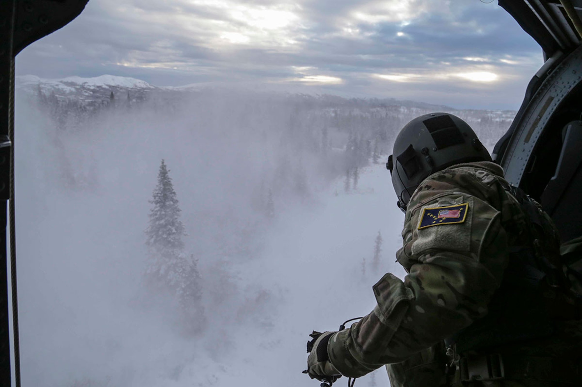 Alaska Air National Guard Staff Sgt. Jheren Svoboda, a flight engineer with the 210th Rescue Squadron, prepares to hoist a combat rescue officer out of an HH-60 Pave Hawk helicopter during a training mission near Mount Susitna Dec. 16, 2014. (U.S. Army National Guard photo/Sgt. Balinda O’Neal)