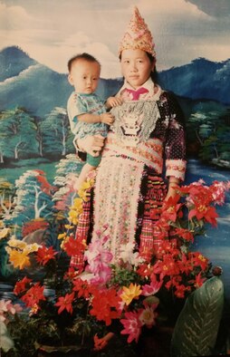 Senior Airman Yia Thao, age 1, poses for a portrait with his mother, Mai Song Her, in traditional Hmong ceremonial attire worn for significant events. Thao is now an U.S. Airman and citizen. (Courtesy photo)