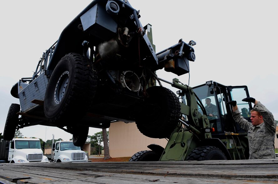 Airman Mitchel Denny, 1st Special Operations Logistics Readiness Squadron vehicle operations, directs a 10 K all terrain fork lift to lower a vehicle onto a trailer at Hurlburt Field, Fla., Feb 24, 2015. Vehicle Operations Flight provides transportation services on demand for Hurlburt Field to include Distinguished Visitor support, base taxi, flight line operations and cargo pick-up and delivery services, and government driver's license issue. (U.S. Air Force photo/Airman 1st Class Andrea Posey)