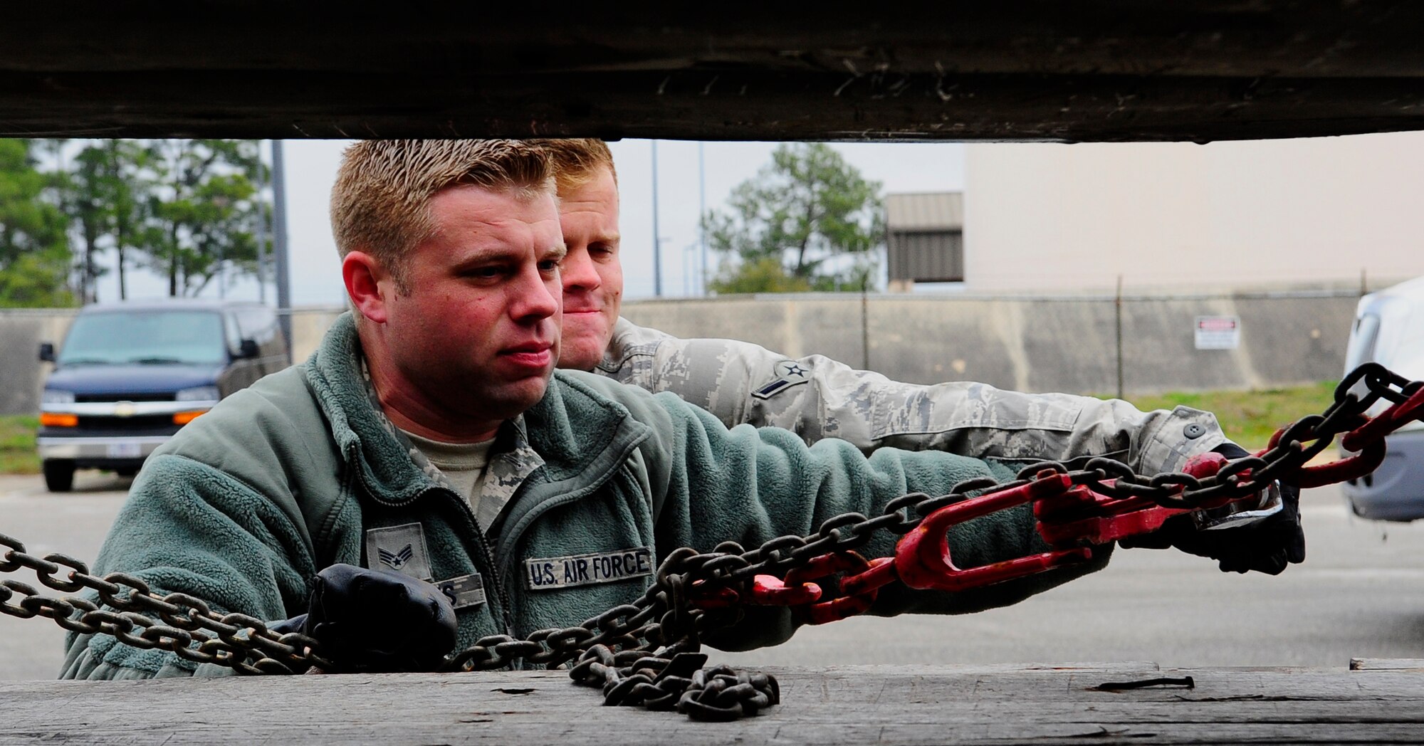 Senior Airman Tristan Roberts and Airman Mitchel Denny, 1st Special Operations Logistics Readiness Squadron vehicle operations, tighten chains to a trailer with a binder at Hurlburt Field, Fla., Feb 24, 2015. Vehicle Operations Flight provides transportation services on demand for Hurlburt Field to include Distinguished Visitor support, base taxi, flight line operations and cargo pick-up and delivery services, and government driver's license issue. (U.S. Air Force photo/Airman 1st Class Andrea Posey)
