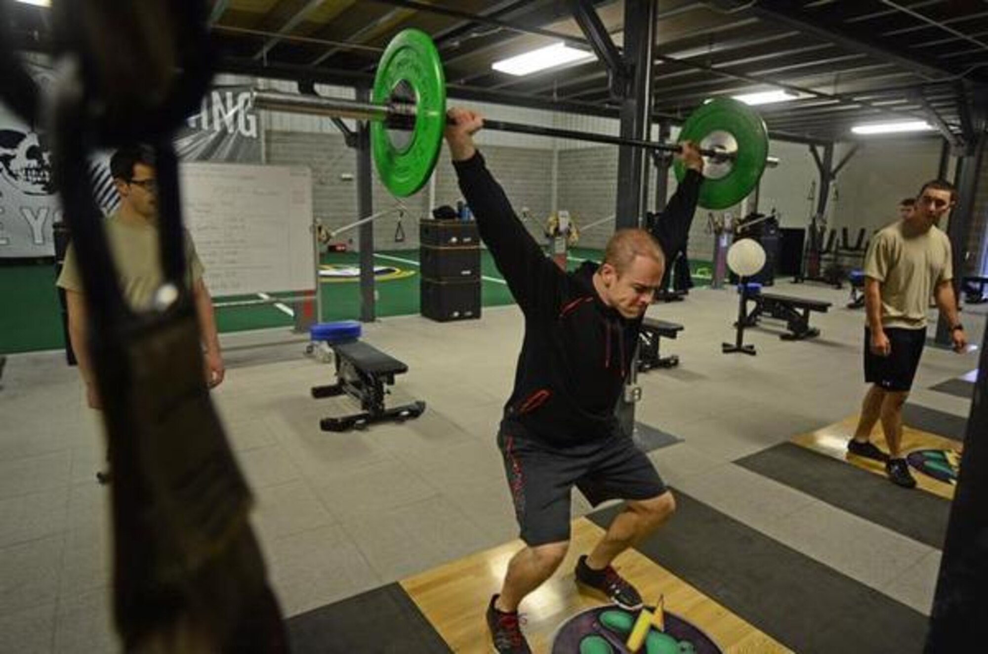 Dan Clemons, 22nd Special Tactics Squadron strength and conditioning coach, demonstrates proper form for a hang snatch exercise during an early morning workout at Joint Base Lewis-McChord, Wash. Clemons supervises daily workouts in the 22 STS state-of the-art facility. (Northwest Guardian/Dean Siemon)