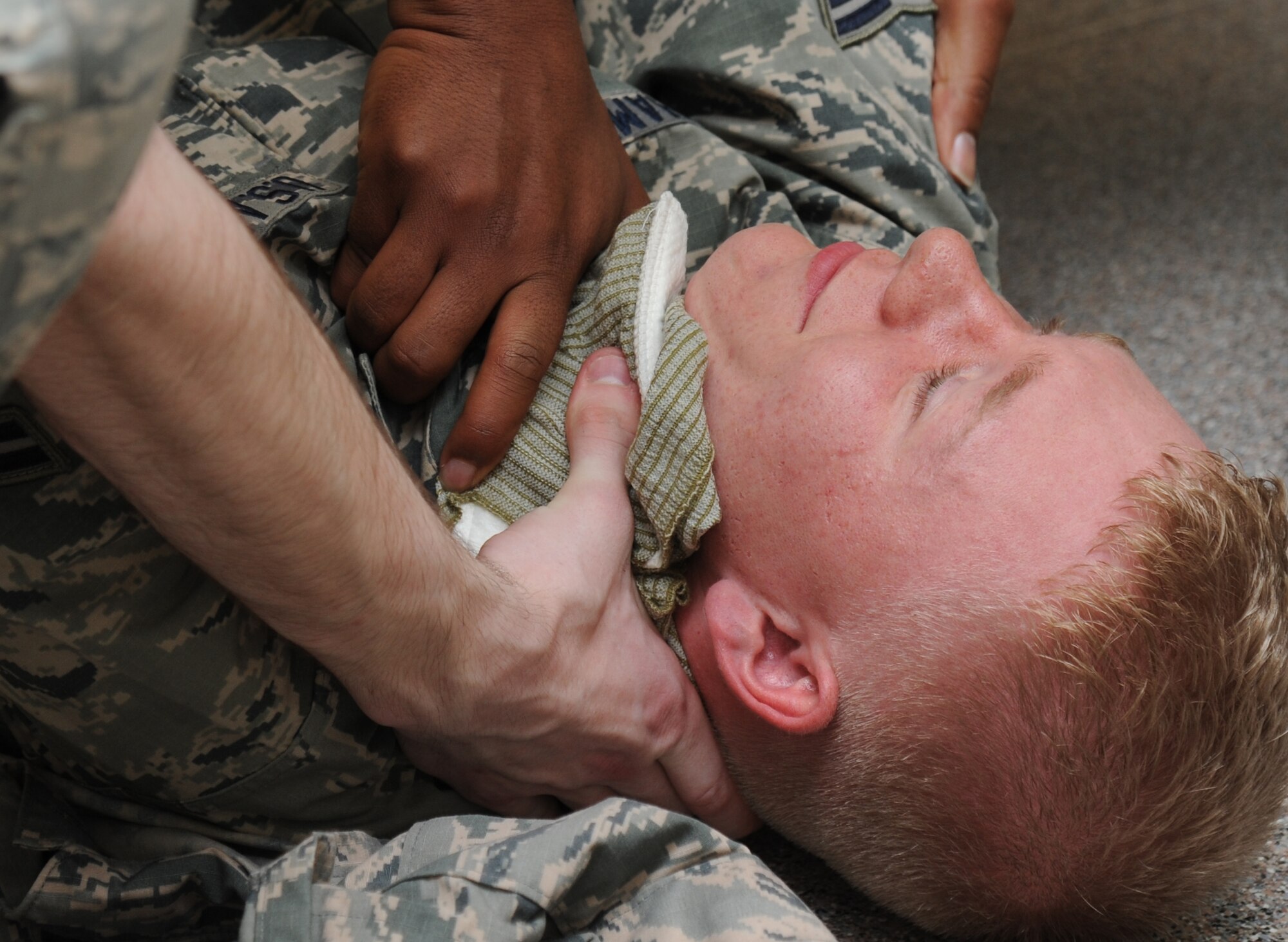 Airman 1st Class Cameron Champ, 335th Training Squadron student, receives self-aid and buddy care while portraying a victim during an “Introduction to Mobility” training day for non-prior service Airmen March 13, 2015, at Davis Manor, Keesler Air Force Base, Miss.  Airmen participated in pre-deployment training scenarios: such as going through a mobility processing line, administering self-aid and buddy care, reviewing the steps for chemical warfare gear and receiving a pre-deployment briefing.  The training was conducted to better prepare Keesler’s Airmen for deployment operations.  (U.S. Air Force photo by Kemberly Groue)