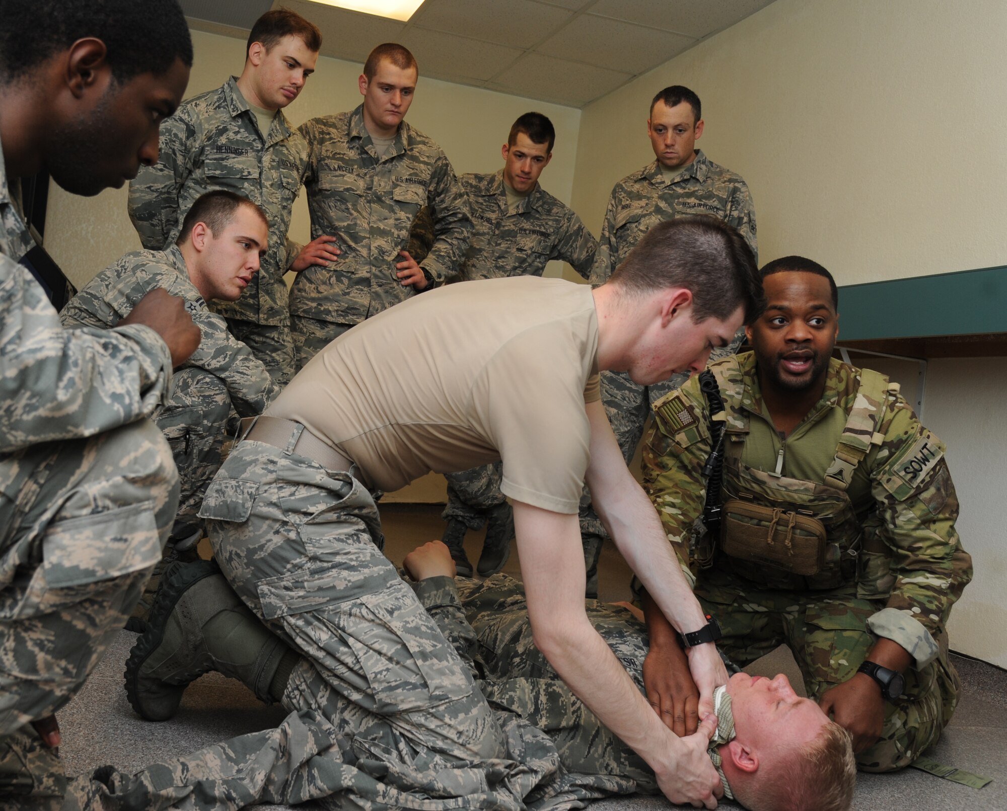 Airman Basic Austin Denney, 335th Training Squadron student, and Master Sgt. Fred Demming, 335th TRS special operations weather instructor, administer self-aid and buddy care on Airman 1st Class Cameron Champ, 335th TRS student, during an “Introduction to Mobility” training day for non-prior service Airmen March 13, 2015, at Davis Manor, Keesler Air Force Base, Miss.  Airmen participated in pre-deployment training scenarios such as: going through a mobility processing line, administering self-aid and buddy care, reviewing the steps for wearing chemical warfare gear and receiving a pre-deployment briefing.  The training was conducted to better prepare Keesler’s Airmen for deployment operations.  (U.S. Air Force photo by Kemberly Groue)