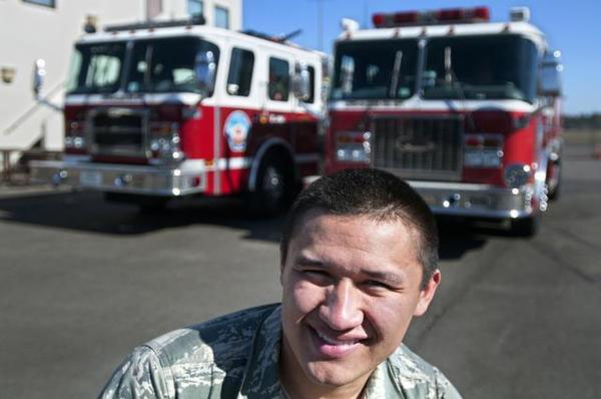 Airman 1st Class James Salazar, 627th Civil Engineer Squadron firefighter, stands before two fire trucks at Joint Base Lewis-McChord. Salazar was recently named winner of the 2014 IMCOM Fire and Emergency Service Award. (Northwest Guardian/Alexandra Kocik)