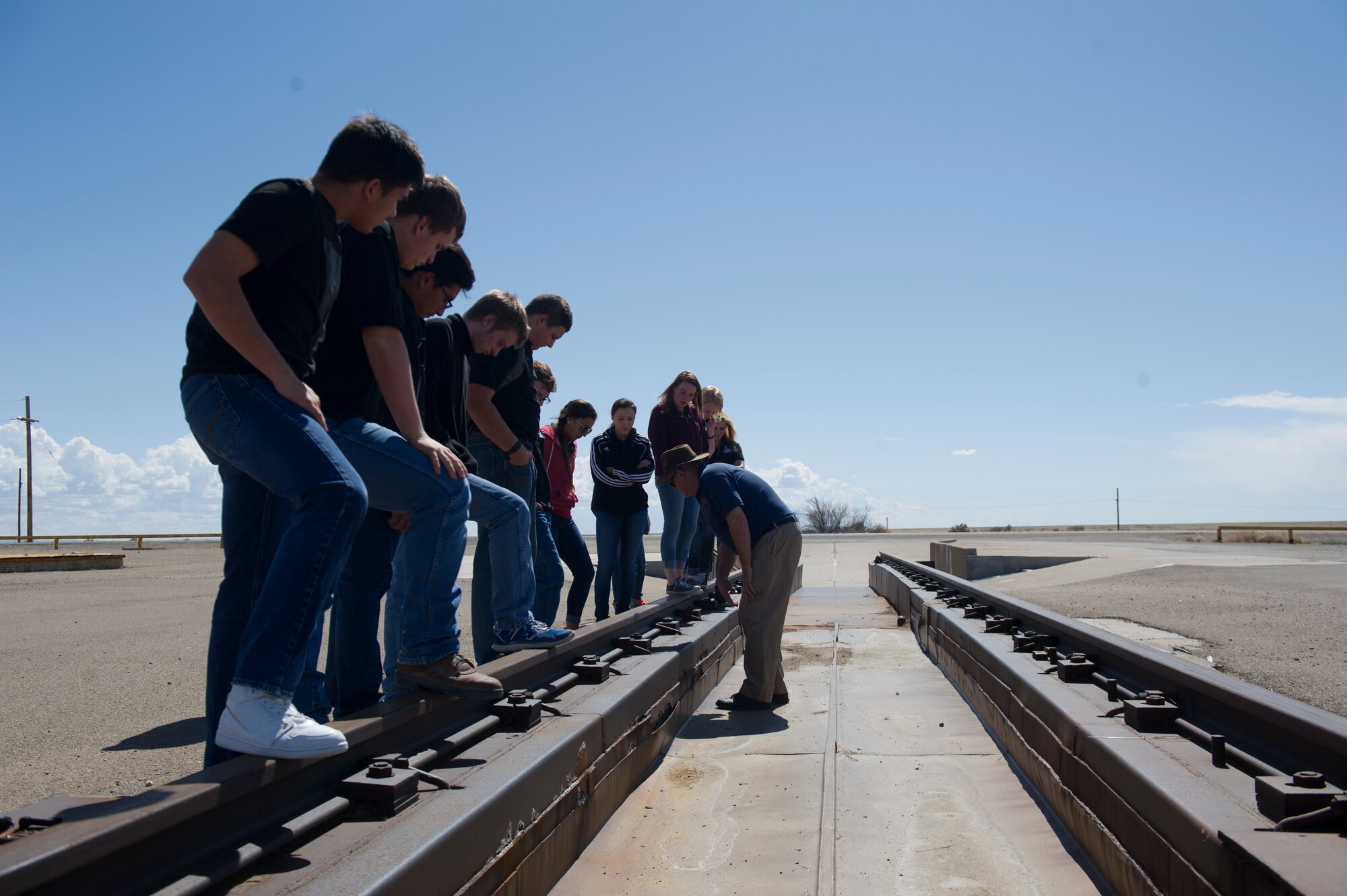 Junior Leadership Otero members stand on Holloman High Speed Test Track, the Air Force’s premiere test track that spans 10 miles. Jim Daniels of the 846th Test Squadron shows the students how the double rail portion of the track operates during a test. This portion of the track is no longer used for actual tests and was part of the original sections built at Holloman. (U.S. Air Force photo by Airman 1st Class Aaron Montoya/RELEASED)