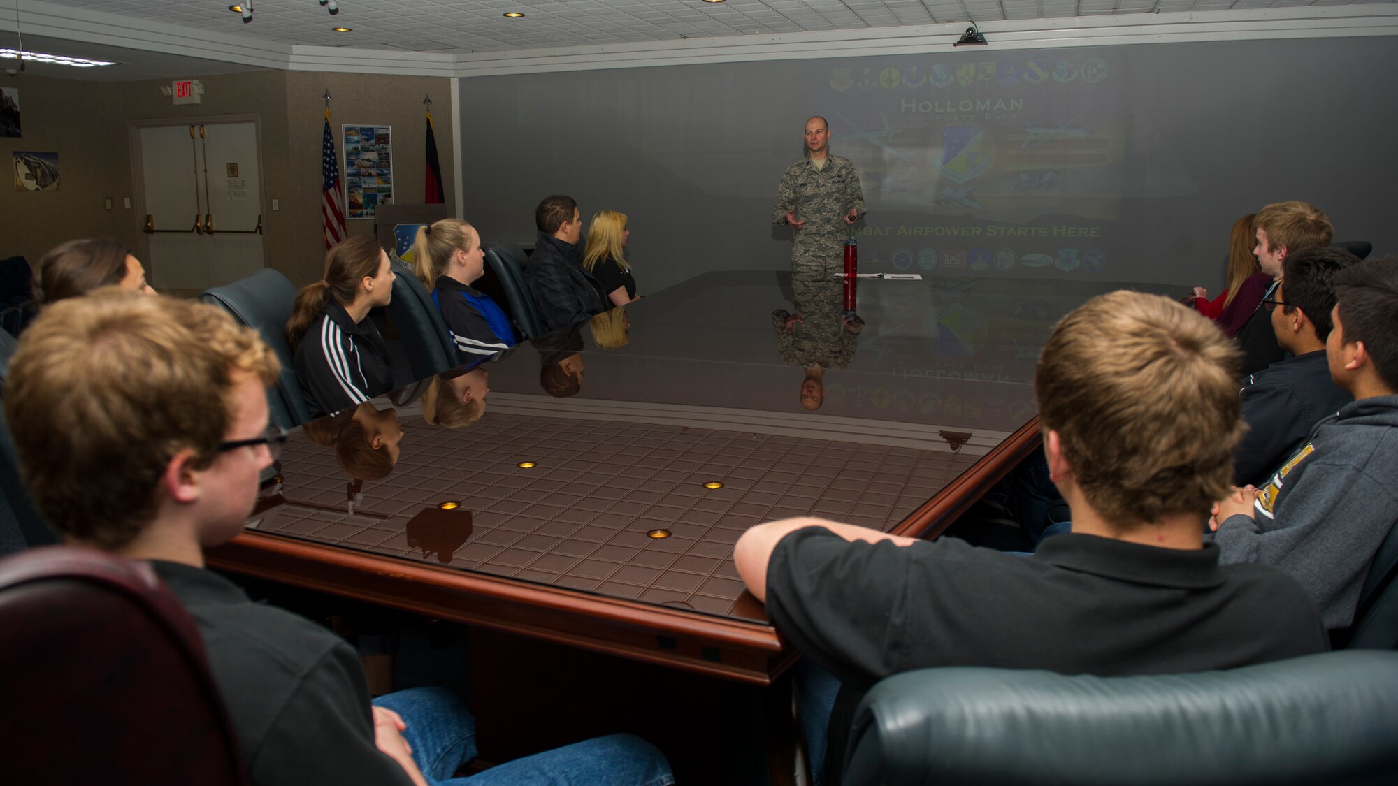 Junior Leadership Otero students sit in the chairs of the 49th Wing Conference Room to hear an introductory brief from the 49th Wing Public Affairs Chief, Capt. Bryant Davis. The students are shown a presentation that highlighted various units present at Holloman. (U.S. Air Force photo by Airman 1st Class Aaron Montoya/RELEASED)