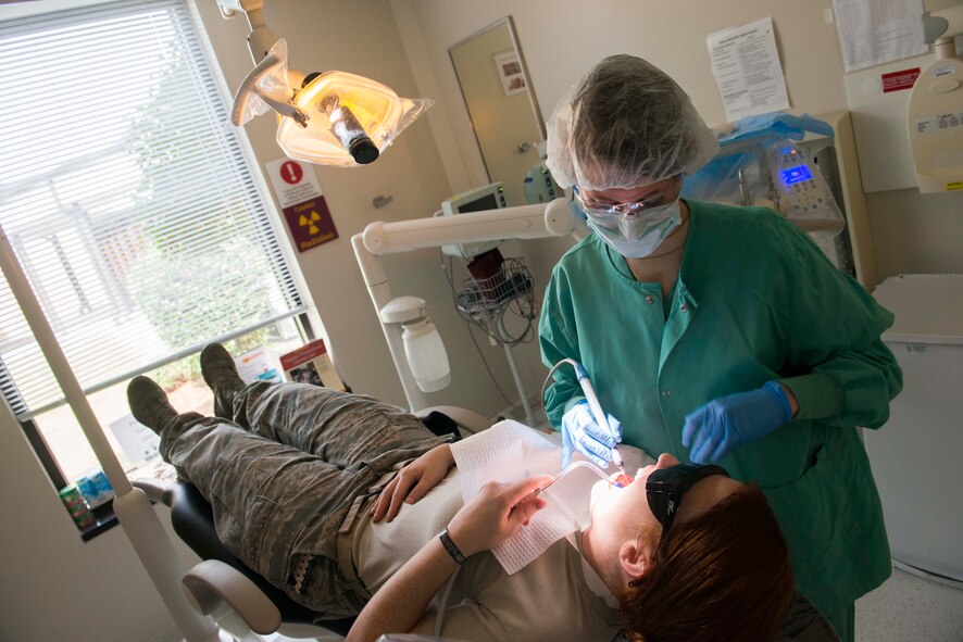 U.S. Air Force Staff Sgt. Julia Frensley, 23d Aerospace Medicine Squadron dental assistant, performs an annual dental cleaning on a patient March 12, 2015, at Moody Air Force Base, Ga.  Routine checkups and cleanings help prevent dental emergencies by identifying issues, such as cavities or chipped teeth. (U.S. Air Force photo by Airman 1st Class Dillian Bamman/Released)
