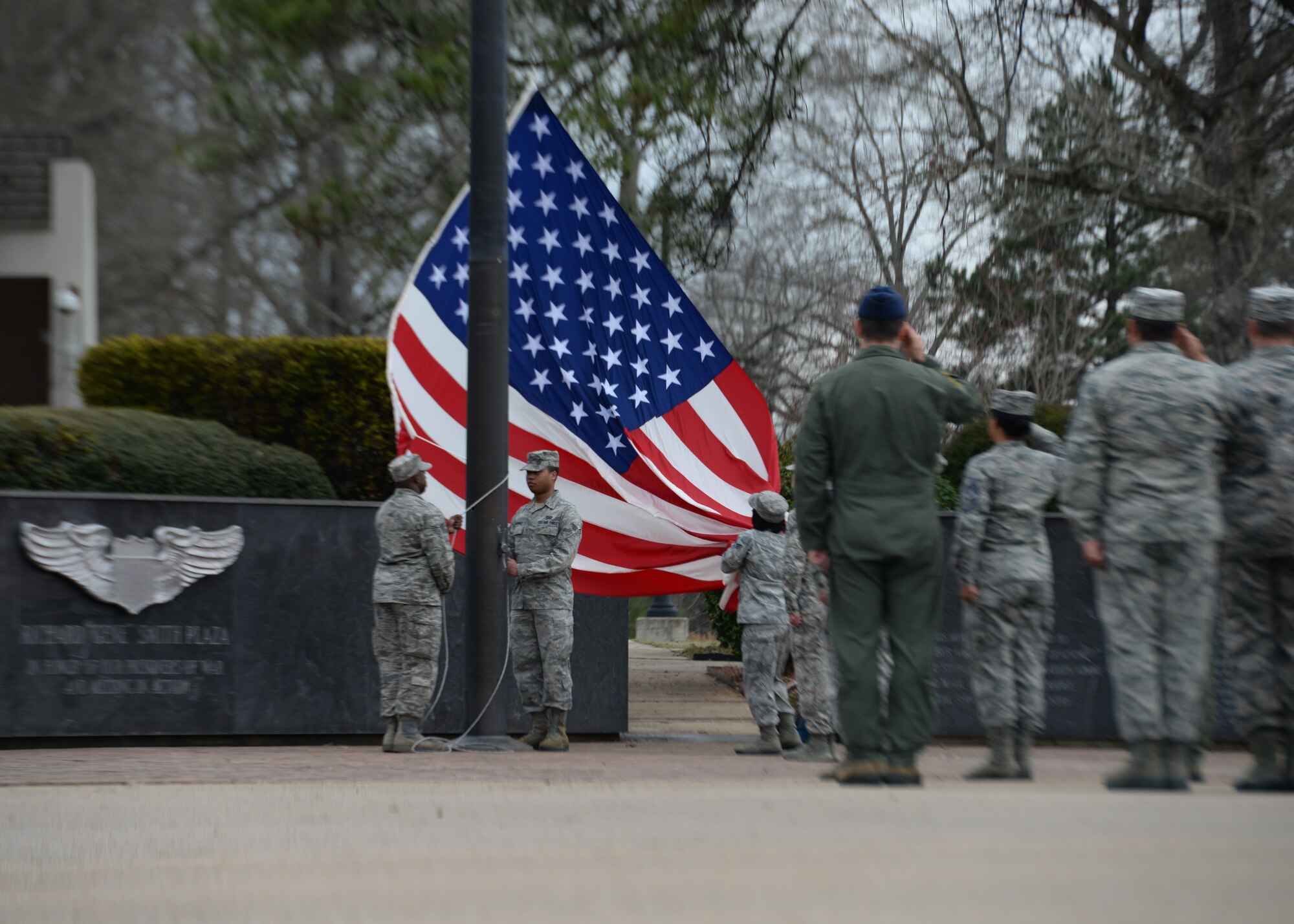 Airmen of Columbus Air Force Base salute as the graduates of Airman Leadership School Class 15-3 lower the flag during a retreat ceremony March 12 at the flag pole in the Richard “Gene” Smith Plaza. ALS is a six week course designed to give the attendees the tools they will need to be future supervisors. (U.S. Air Force Photo/Senior Airman Stephanie Englar)