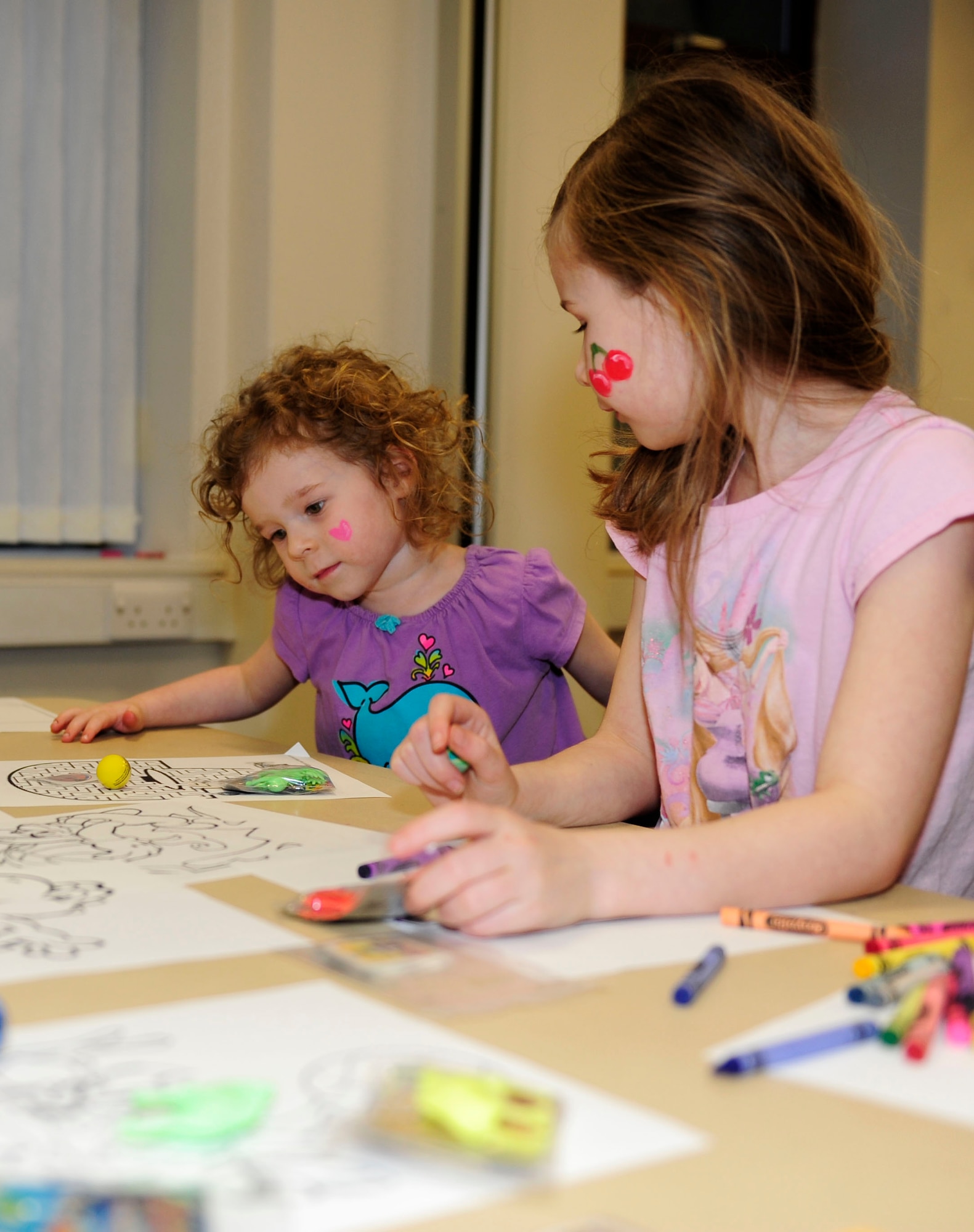 A three-year-old girl, left, and her eight-year-old sister, right, daughters of a deployed Airman, color during the monthly Hearts Apart event March 12, 2015, at the chapel on RAF Mildenhall, England. A Hearts Apart dinner is an opportunity for spouses and family members of deployed Airmen to gather and show support for one another. (U.S. Air Force photo/Staff Sgt. Krystie Martinez/Released)