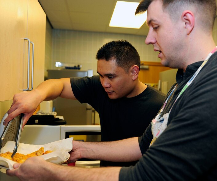 U.S. Air Force Tech. Sgt. Ervin Yamzon, left, 100th Maintenance Squadron programs manager, from Agana Heights, Guam, and U.S. Air Force Staff Sgt. Ryan McAuley, right, 100th MXS fuel systems craftsman from Salem, Ore., prepare a meal for the monthly Hearts Apart event March 12, 2015, at the chapel on RAF Mildenhall, England. A Hearts Apart dinner is an opportunity for spouses and family members of deployed Airmen to gather and show support for one another. (U.S. Air Force photo/Staff Sgt. Krystie Martinez/Released)