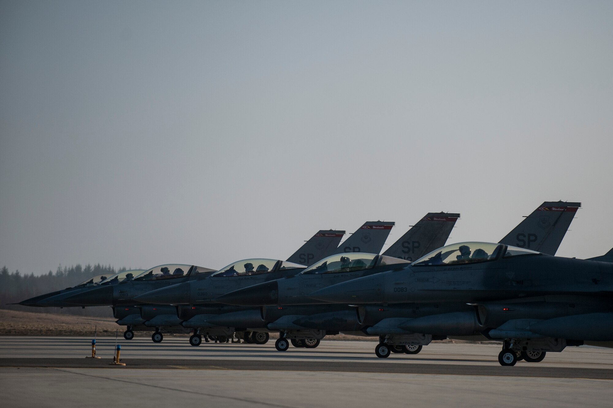 A row of U.S. Air Force F-16 Fighting Falcon fighter aircraft assigned to the 480th Fighter Squadron prepares to taxi on the runway at Spangdahlem Air Base, Germany, March 13, 2015. The aircraft will participate in Dacian Warhawk 2015, a bilateral flying training deployment between the U.S. and Romanian air forces at Campia Turzii, Romania, March 16-27, 2015. The exercise aims to strengthen the NATO partners’ interoperability and their readiness to conduct combined air operations. (U.S. Air Force photo by Senior Airman Rusty Frank/Released)