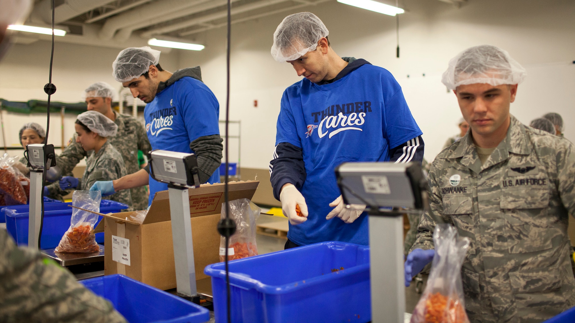 Oklahoma City Thunder players Enes Kanter, left, and Steve Novak and Staff Sgt. Timothy Schwanke, from the 960th Airborne Air Control Squadron, package carrots during a joint NBA and Department of Defense volunteer event at the Regional Food Bank of Oklahoma on Monday. Also pictured are Soldiers from the Oklahoma Army National Guard. (Photo courtesy of Regional Food Bank of Oklahoma)