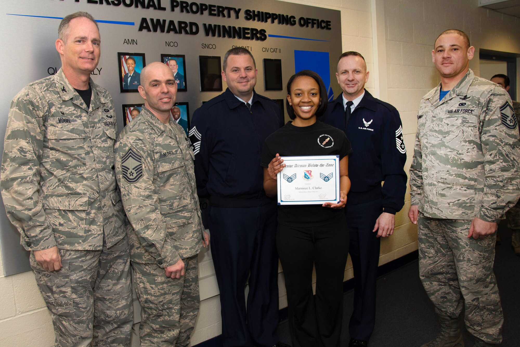 66th Air Base Group Commander Col. Michael A. Vogel and Hanscom Command Chief Master Sgt. Craig A. Poling and other enlisted senior leaders present newly promoted Senior Airman Marniece Clarke, Joint Personal Property Shipping Office storage management technician, with a certificate for a below-the-zone promotion to senior airman at her office on base March 13. Clarke and five others met a BTZ promotion board earlier in the day for the early promotion. BTZ is a competitive early promotion program offered to those in the rank of airman first class who stand out from their peers. (U.S. Air Force photo by Mark Herlihy)
