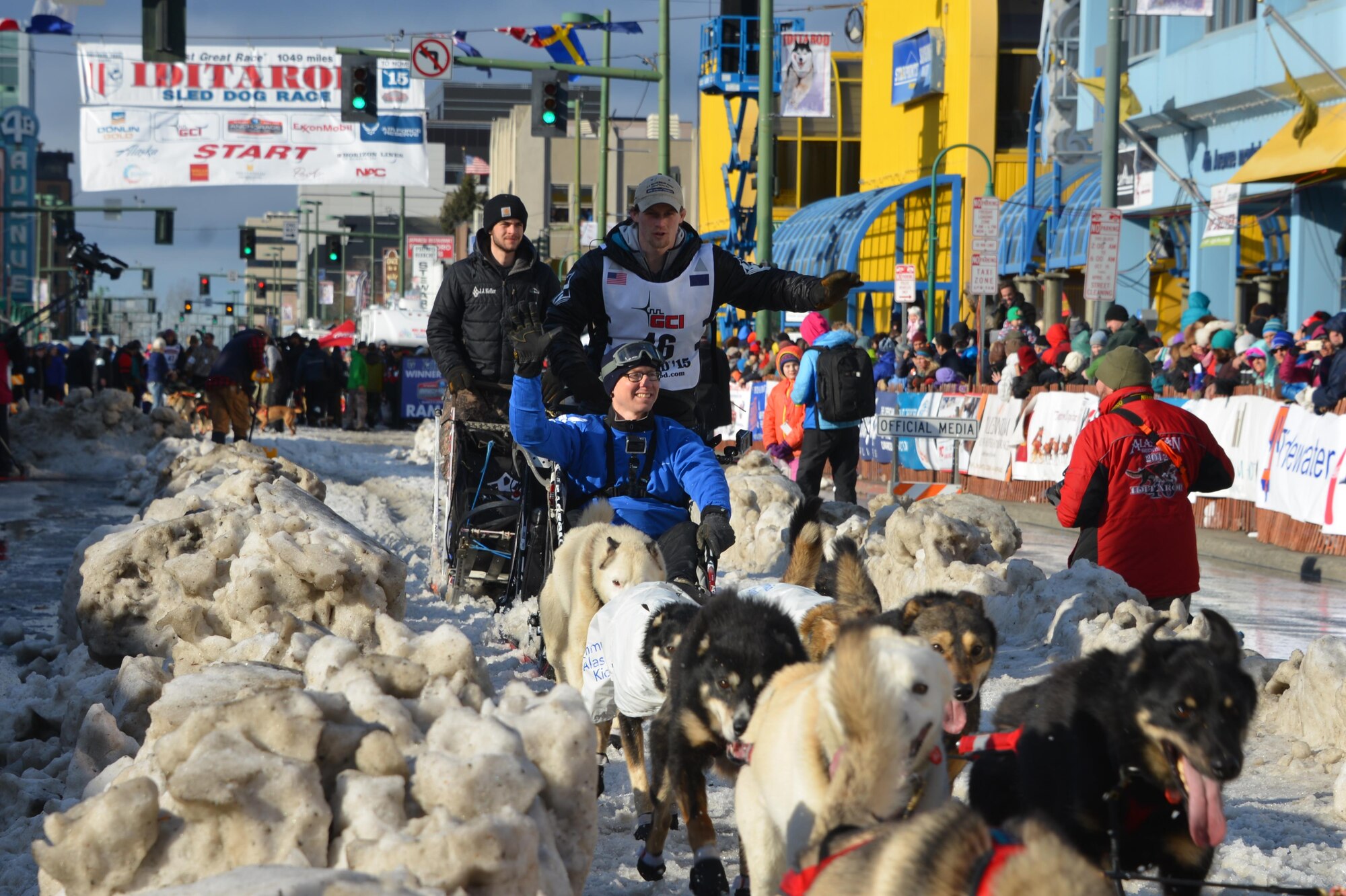 Tech Sgt. Gerald Ingram waves at the crowd while riding on the sled of reigning Iditarod Champion, Dallas Seavey, during the 2015 Iditarod Ceremonial Start.This year marks the 43rd running of the Iditarod and the first year of the Air Force Reserve’s sponsorship. (U.S. Air Force/Capt. Megan Liemburg-Archer)