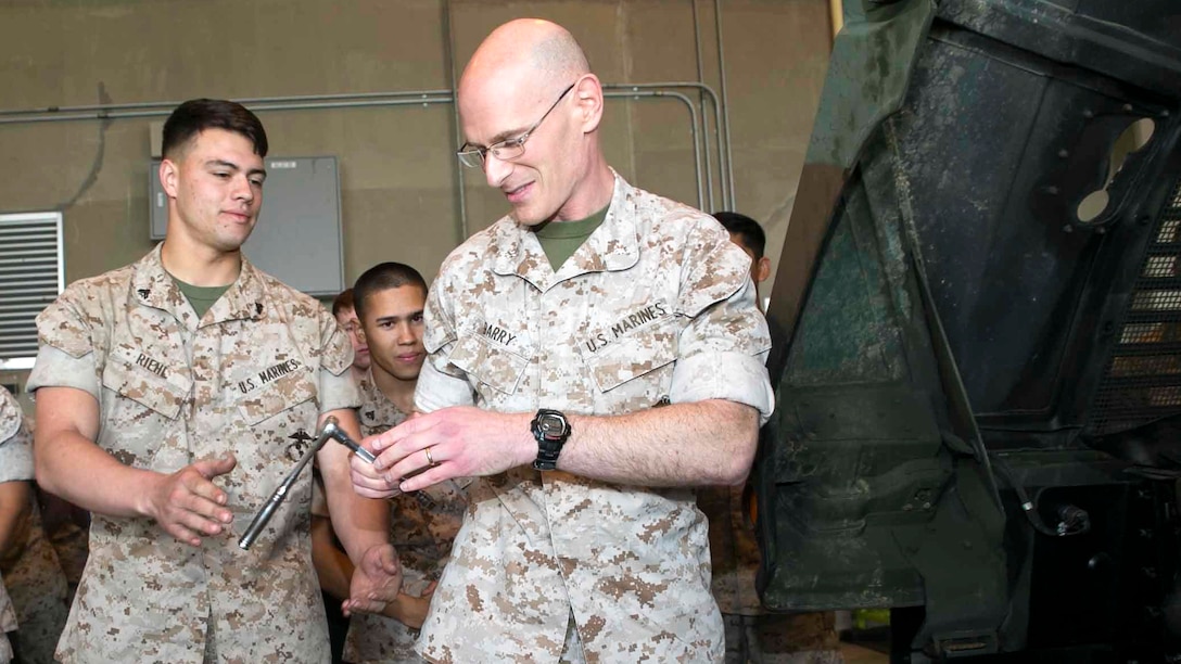 Cpl. John T. Riehl, left, hands Lt. Col. John C. Barry a socket wrench so he can put the last bolt in a Humvee March 13 on Marine Corps Air Station Futenma. The final bolt in the Humvee made Marine Air Control Squadron 4 the only unit in the Marine Corps to be at 100 percent equipment readiness. MACS-4 has over 140 pieces of equipment they must maintain. Riehl is an automotive organizational mechanic with MACS-4, Marine Air Control Group 18, 1st Marine Aircraft Wing, III Marine Expeditionary Force. Barry is the commanding officer of MACS-4.