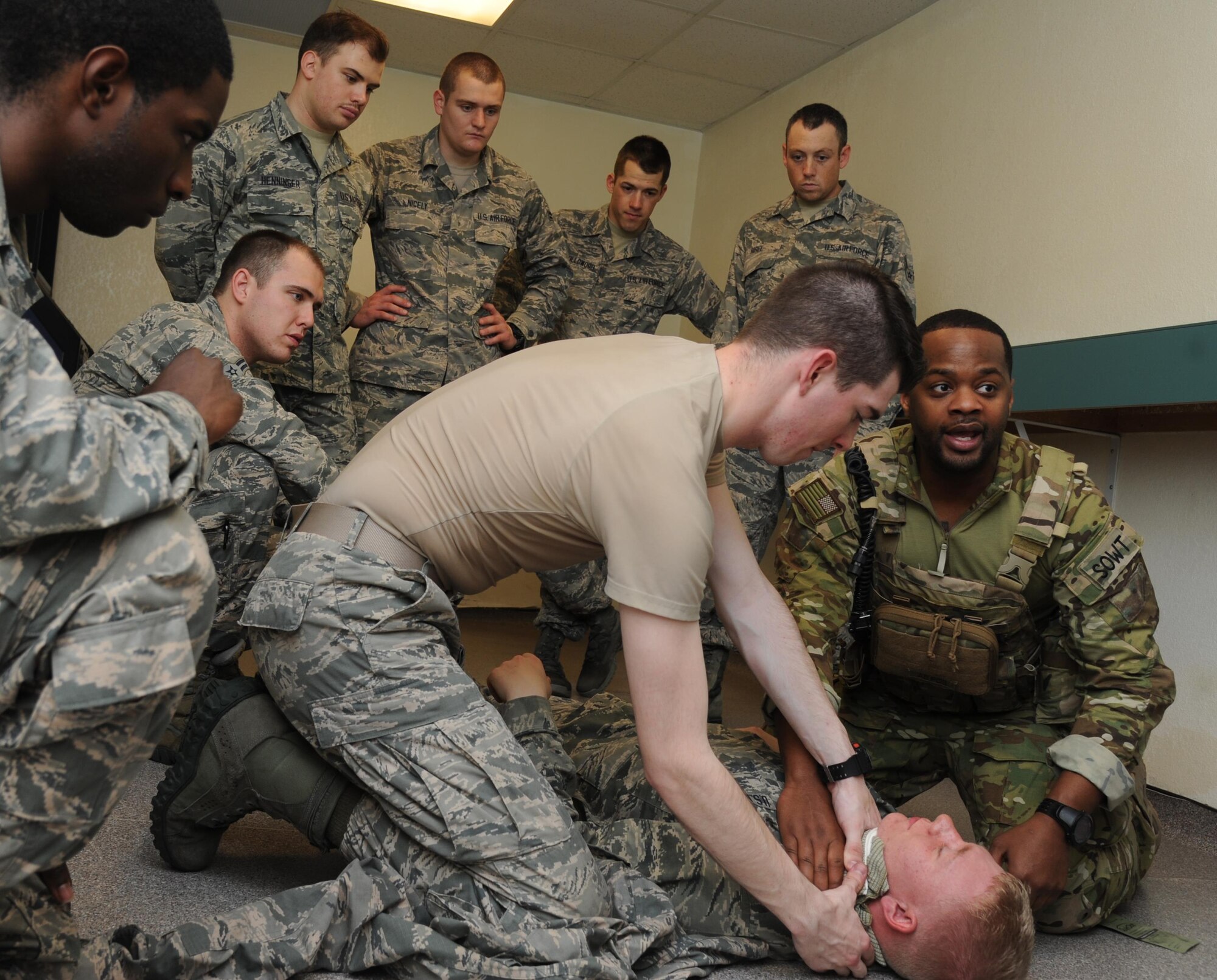 Airman Basic Austin Denney, 335th Training Squadron student, and Master Sgt. Fred Demming, 335th TRS special operations weather instructor, administer self-aid and buddy care on Airman 1st Class Cameron Champ, 335th TRS student, during an “Introduction to Mobility” training day for non-prior service Airmen March 13, 2015, at Davis Manor, Keesler Air Force Base, Miss. Airmen participated in pre-deployment training scenarios such as: going through a mobility processing line, administering self-aid and buddy care, reviewing the steps for wearing chemical warfare gear and receiving a pre-deployment briefing. The training was conducted to better prepare Keesler’s Airmen for deployment operations. (U.S. Air Force photo by Kemberly Groue)