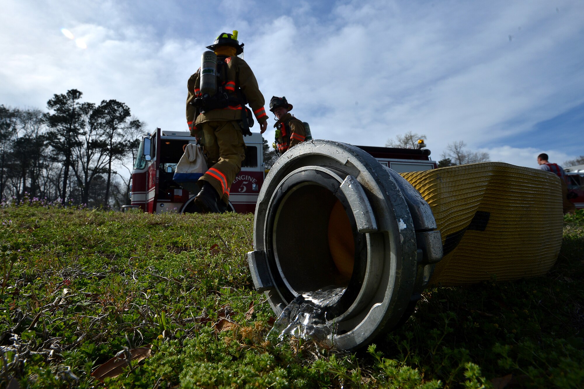 Water leaks out of a fire hose after being unhooked as U.S. Air Force Airmen assigned to the 20th Civil Engineer Squadron fire department attempt to put out a brush fire just outside of the main gate at Shaw Air Force Base, S.C., March 16, 2015. The fire department responded to a brush fire in which it took three minutes to arrive on scene. (U.S. Air Force photo by Staff Sgt. Kenny Holston/Released)