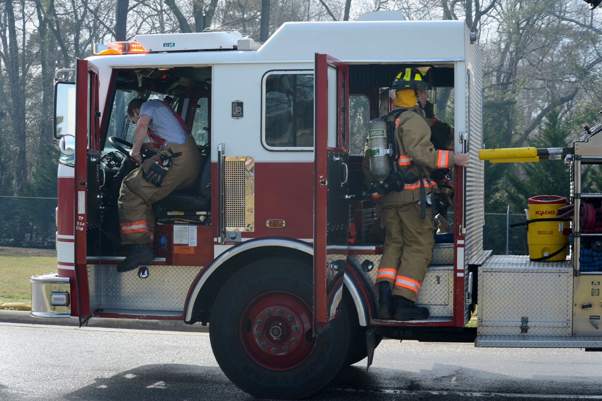 U.S. Air Force Airmen assigned to the 20th Civil Engineer Squadron fire department get into their fire engine enroute to a brush fire near the main gate at Shaw Air Force Base, S.C., March 16, 2015. After arriving onscene within three minutes of the call, the team suppressed the fire before assisting the Sumter County Fire Department off-base. (U.S. Air Force photo by Senior Airman Jensen Stidham/Released) 