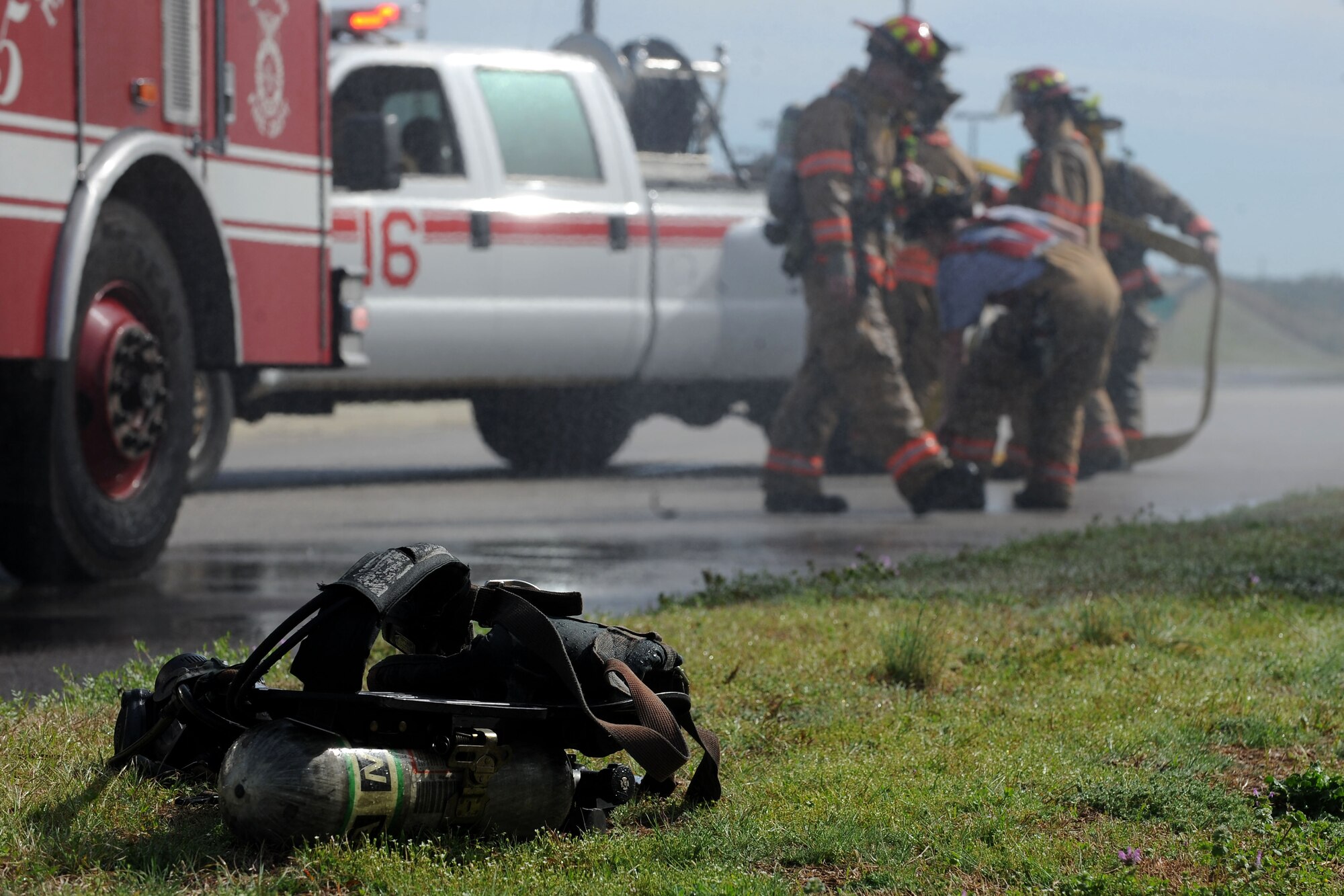 U.S. Air Force Airmen assigned to the 20th Civil Engineer Squadron fire department unreel a firehose at Shaw Air Force Base, S.C., March 16, 2015. The fire department responded to a brush fire in which it took three minutes to arrive on scene. (U.S. Air Force photo by Airman 1st Class Michael Cossaboom/Released)