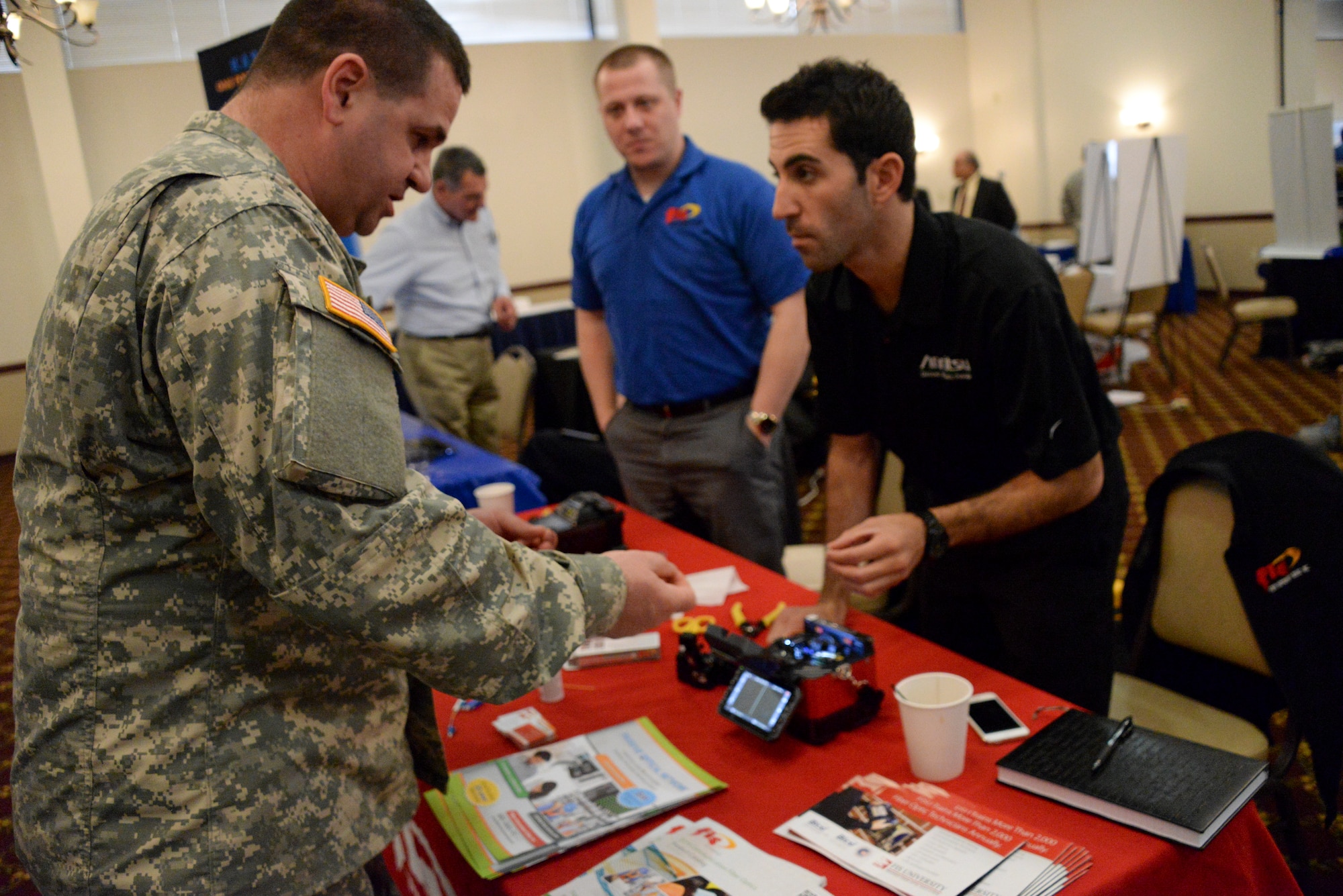 Sgt. 1st Class Leon Miles, Combat Life Saver Course instructor with the 3rd Battalion, 3-312th Regiment, 174th Infantry Brigade, is shown how a new fusion splicer by Anthony Russo, participating vendor at the 7th Annual Joint Base McGuire-Dix-Lakehurst Information Technology Expo held at Tommy B's Community Activities Center on JB MDL, N.J., March 11, 2015. Nearly 60 vendors from across the country came to the joint base to share the technological advancements to the joint base community. (U.S. Air Force photo by Airman 1st Class Tara A. Williamson/Released)