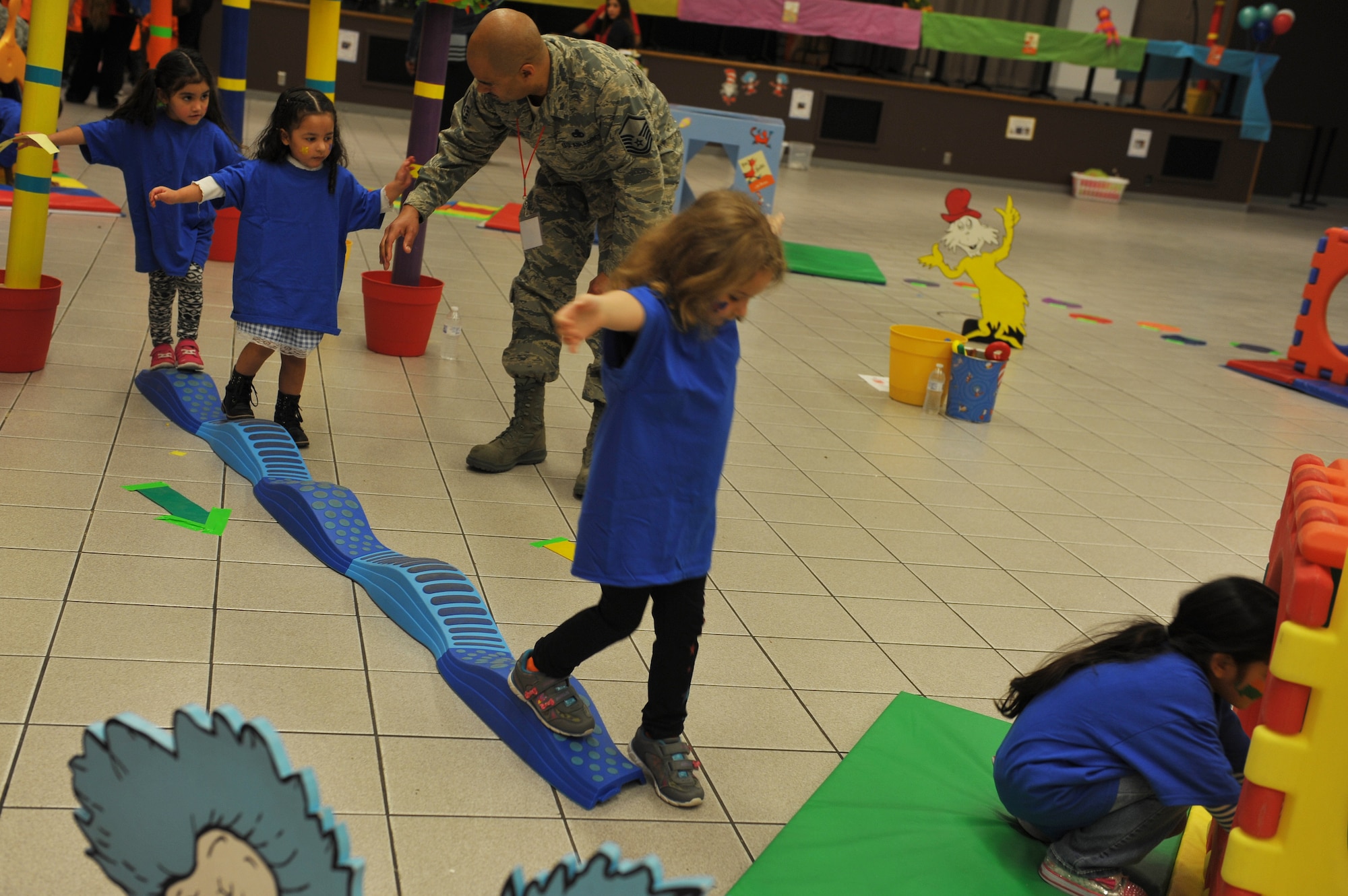Master Sgt. Erique Diggs, 22nd Aircraft Maintenance production supervisor, assists a child through an obstacle course during the 22nd Annual Green Eggs and Ham event at Beech Activity center March 11, 2015 in Wichita, Kan. Green Eggs and Ham is designed to get children excited about reading.  (U.S. Air Force photo by 2nd Lt. Krystal Jimenez)
