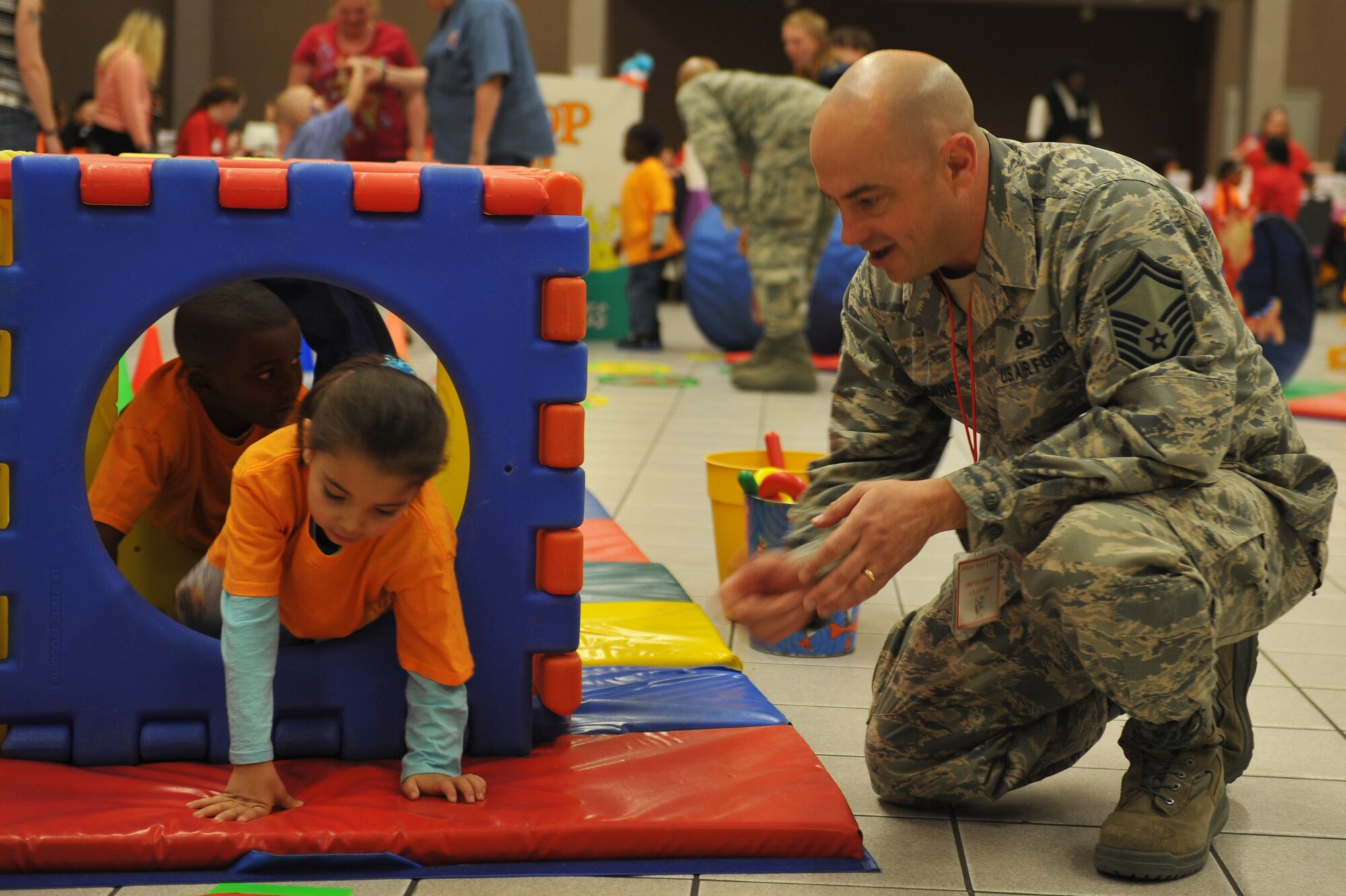 Senior Master Sgt. Randy Simmons (right), 22nd Aircraft Maintenance squadron unit supervisor assists children through an obstacle course during the 22nd Annual Green Eggs and Ham event at Beech Activity center March 11, 2015 in Wichita, Kan. Green Eggs and Ham is designed to get children excited about reading.  (U.S. Air Force photo by 2nd Lt. Krystal Jimenez)